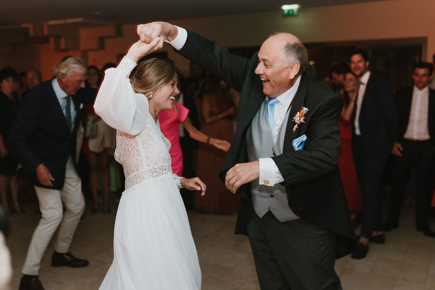 Two people dancing together at a wedding reception, the bride in a white dress and a man in formal attire.