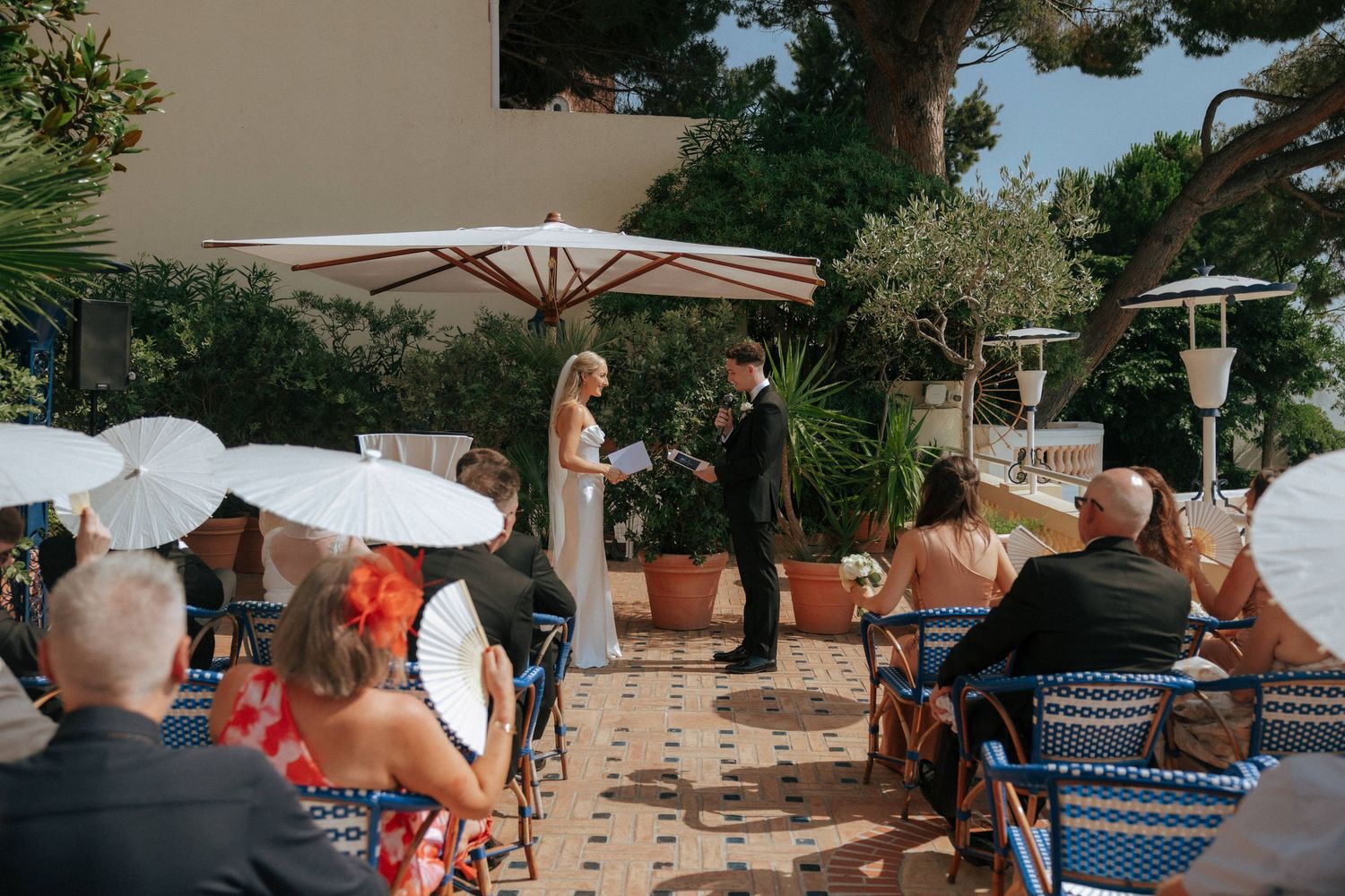 A group gathers under shade umbrellas for an outdoor gathering during a sunny afternoon.