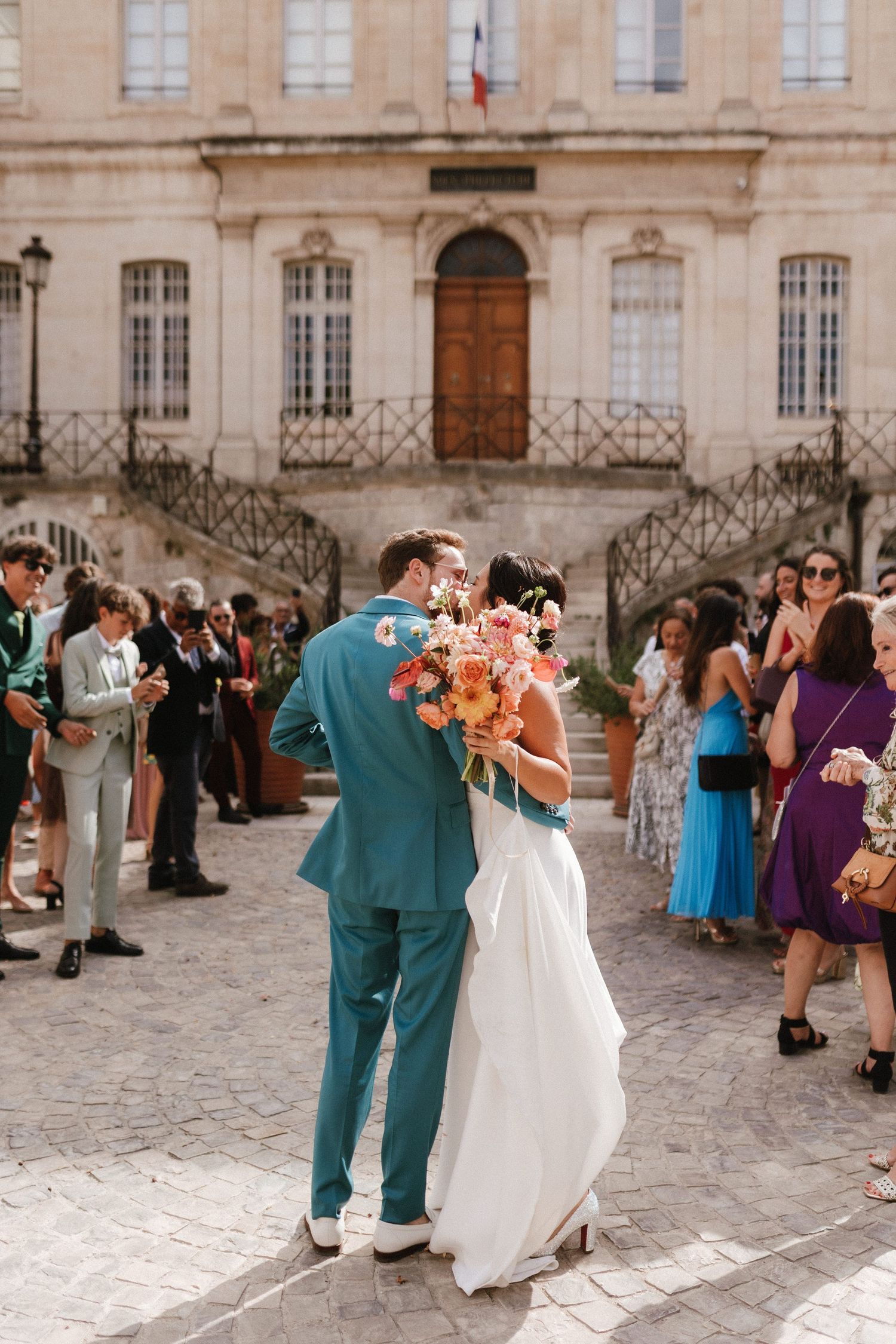 A couple shares their first dance at an elegant French wedding with guests looking on.