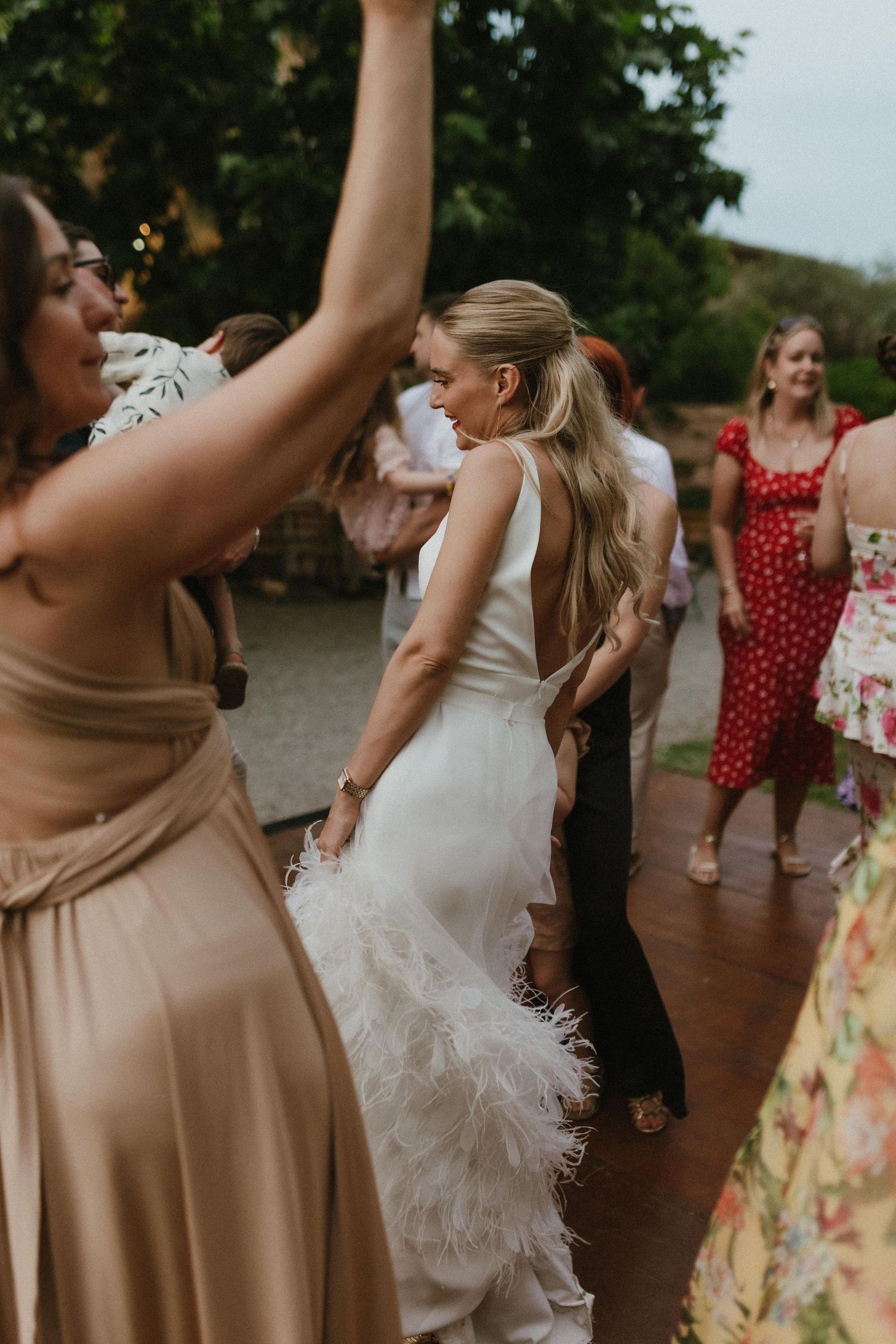 Wedding guests dancing and celebrating at a reception, with a bride in a white dress and attendees in elegant attire.