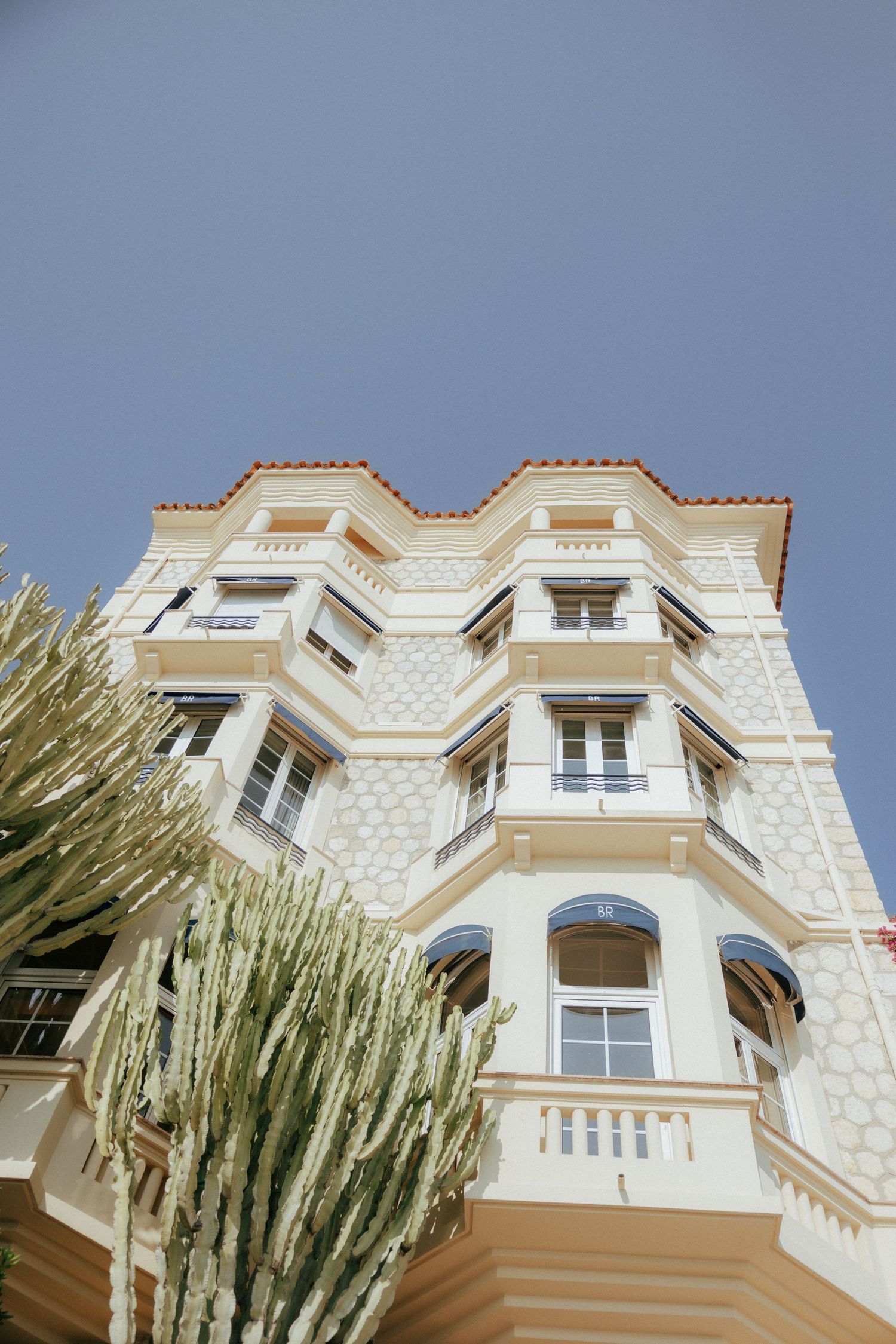 Modern luxury townhouse with stone facade and dormer windows viewed from different low angles against blue sky.
