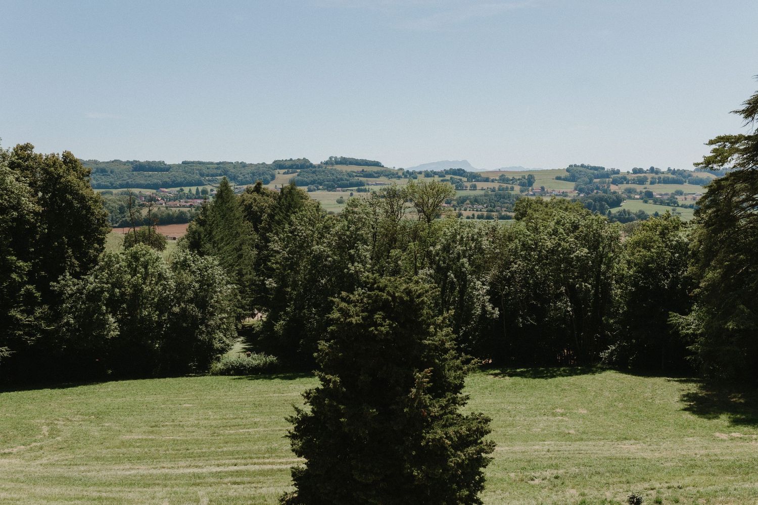 Rolling green hills and forested landscape stretch across a scenic rural countryside on a sunny day.
