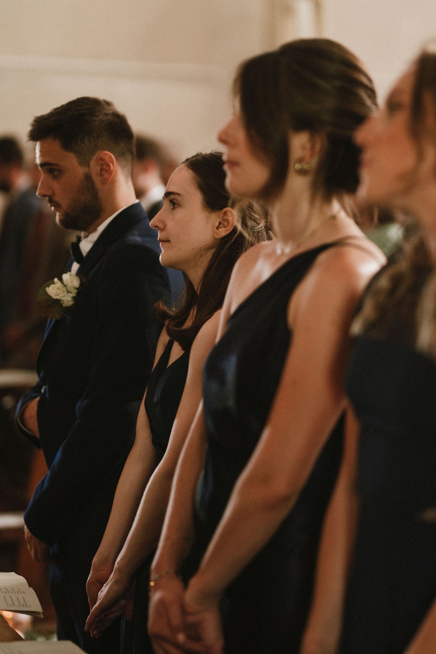 Wedding party members standing together in formal attire during ceremony.