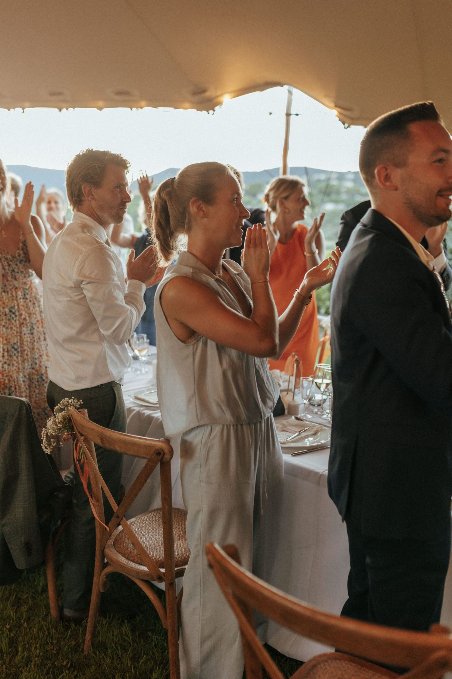 Wedding guests celebrating and cheering during the reception under a tent.