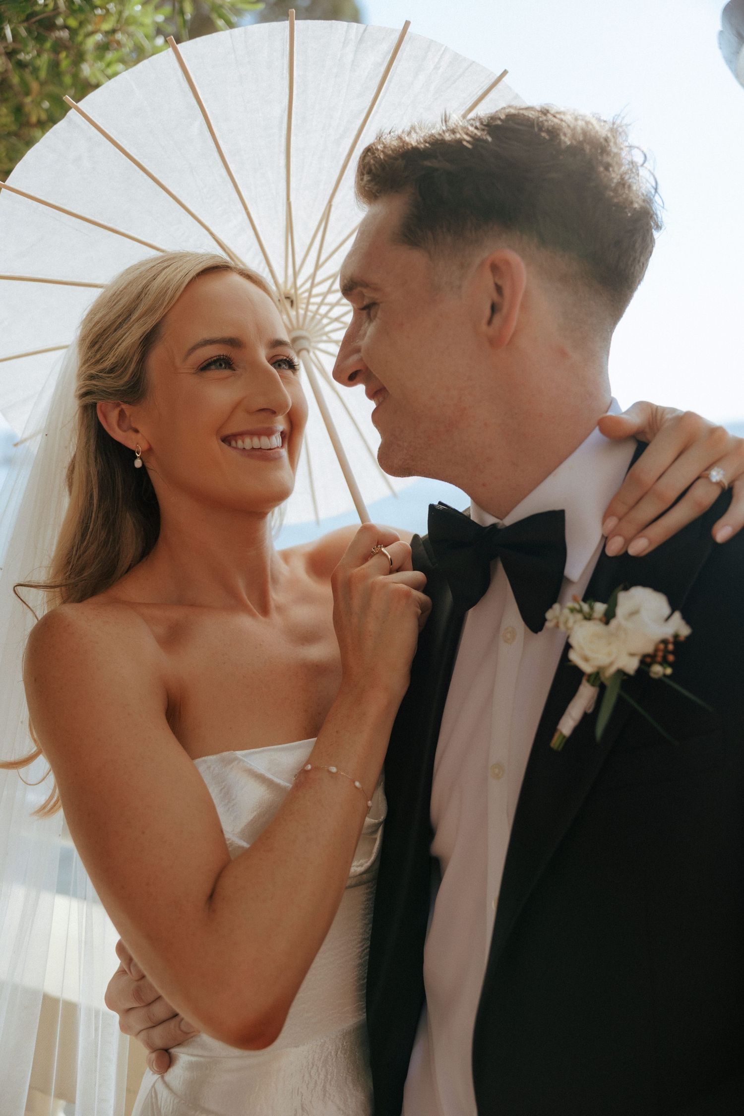 Close-up romantic wedding photos with couple sharing tender moments under a white parasol in natural lighting.