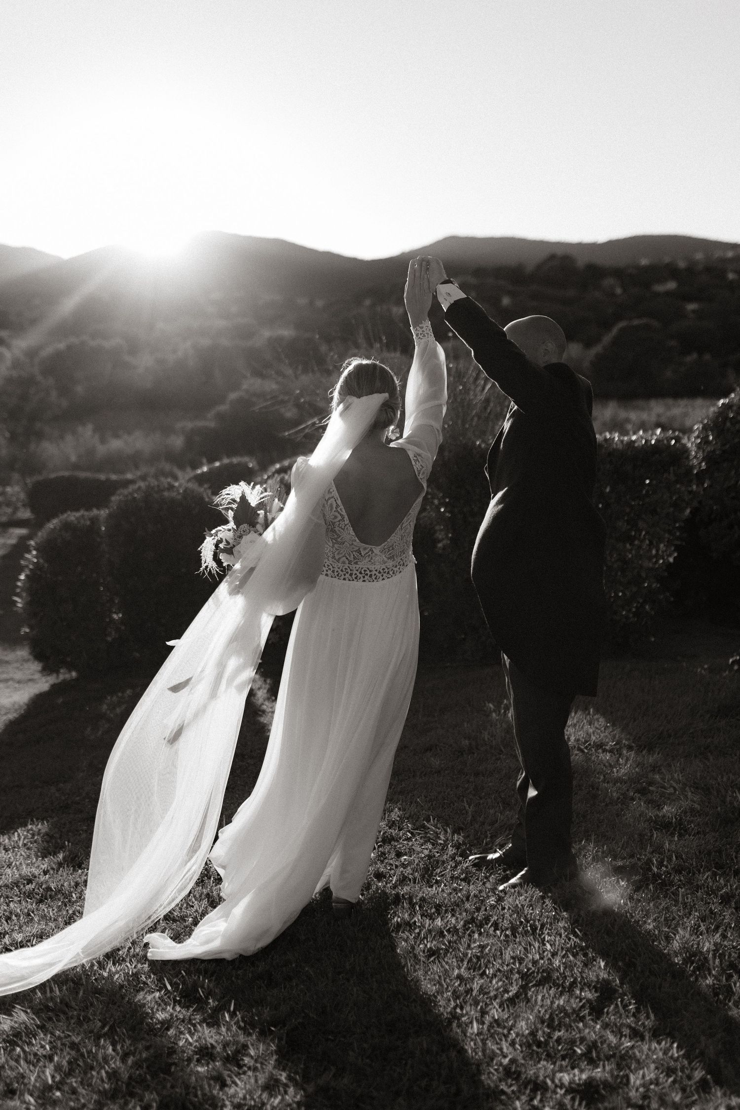 Silhouetted couple dances at sunset with mountains in background.