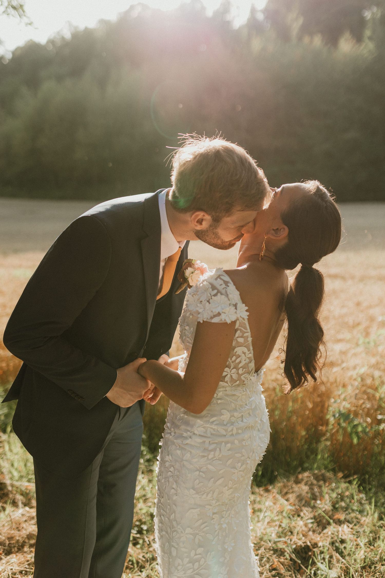 A romantic sunset moment between newlyweds in a golden field.