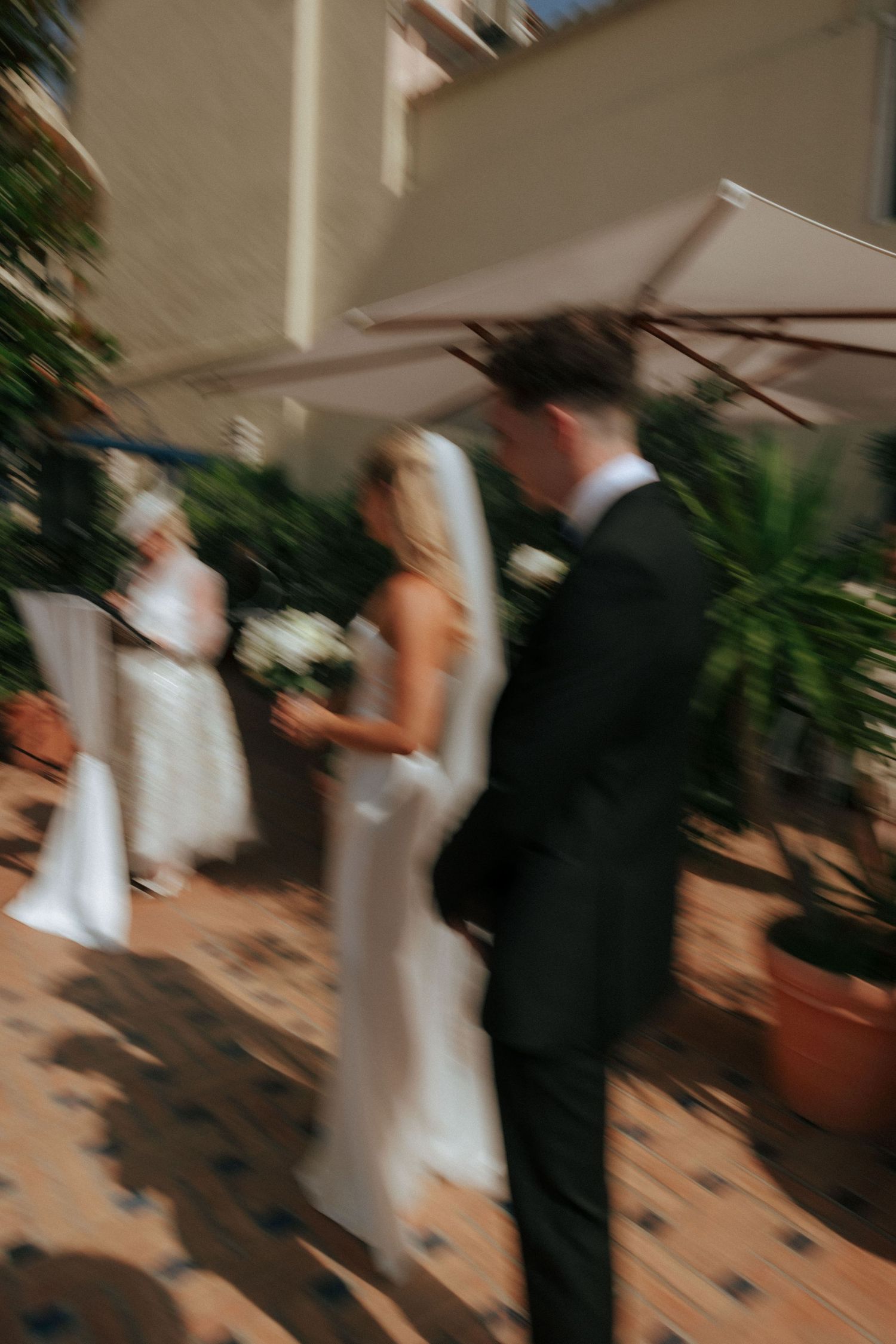 A wedding ceremony taking place under a white umbrella with potted plants in the background.