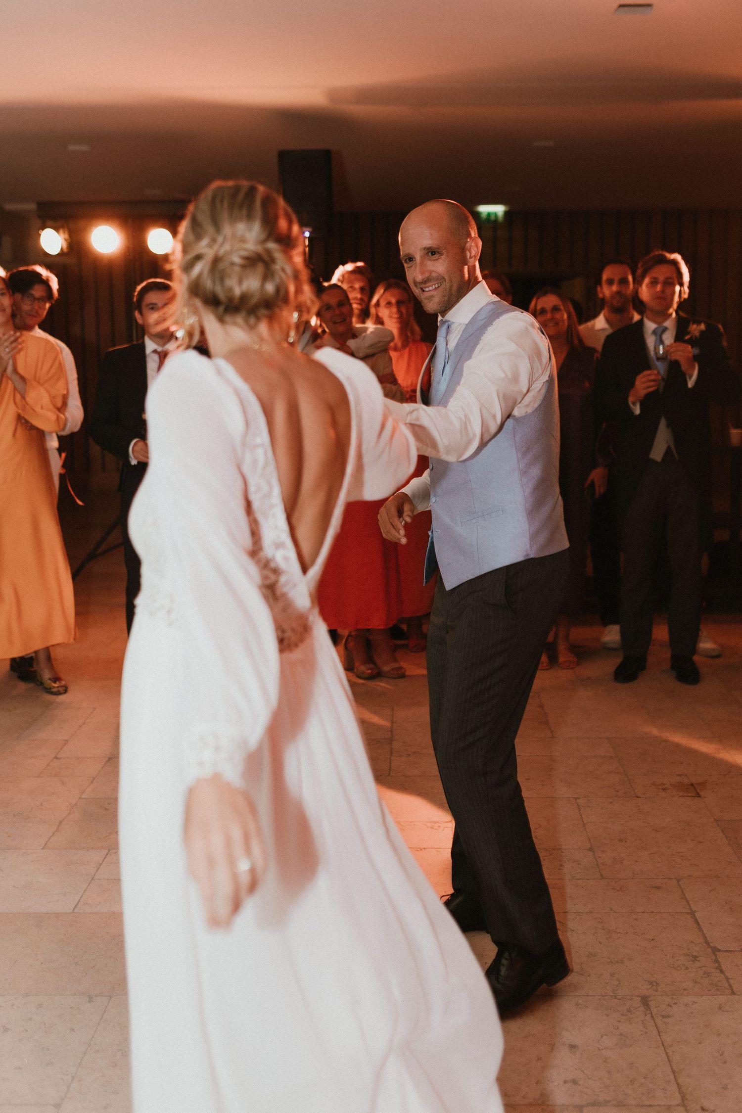 Wedding couple dancing together on an illuminated dance floor while guests watch and celebrate their special moment.