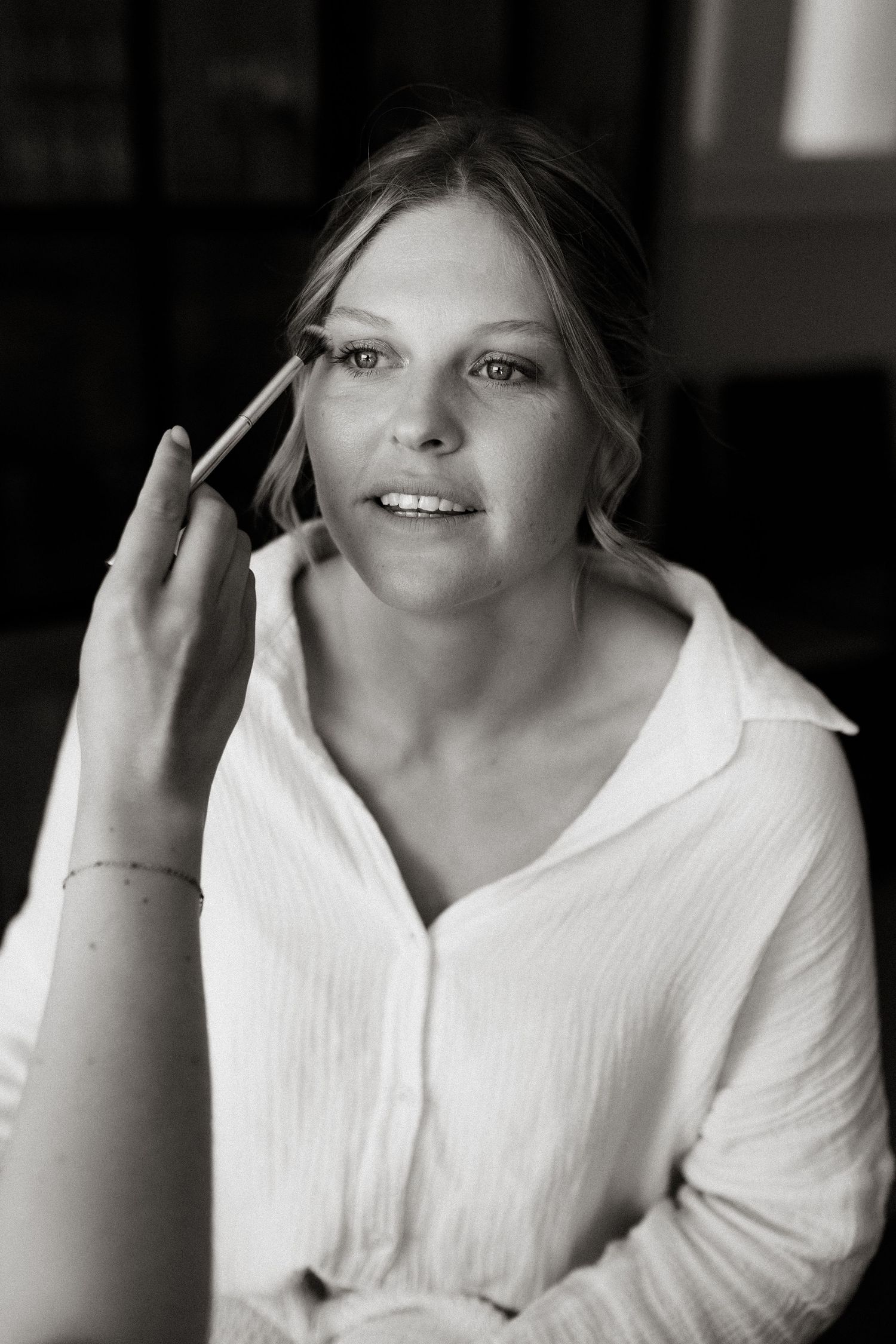 Black and white portrait of someone in a white button-down top looking delighted while gesturing with their hand.