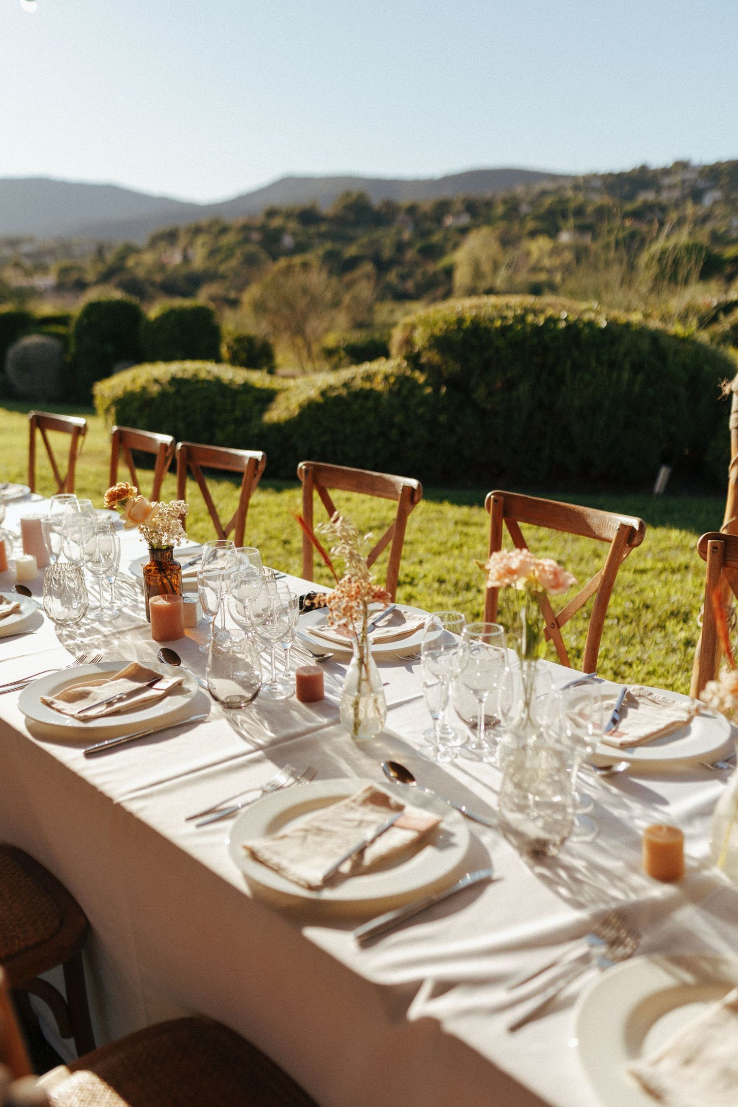 Elegant table setting at outdoor wedding reception with mountain views and cross-back wooden chairs.