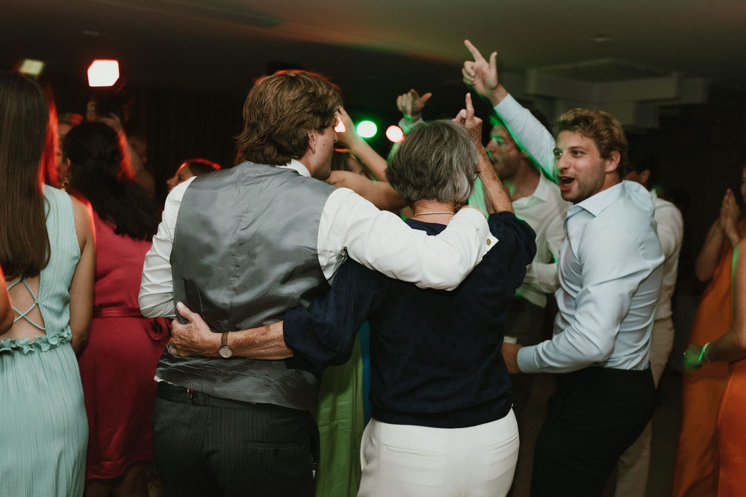 Energetic dancing and celebration at dimly lit wedding reception.
