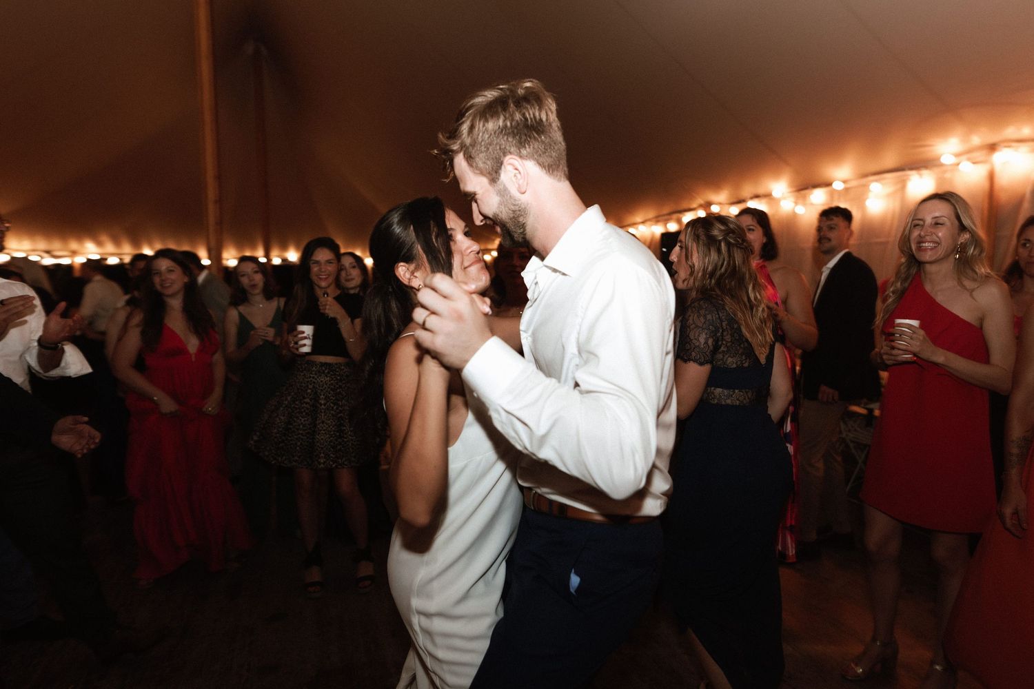 A couple dances intimately at their wedding reception under warm lighting.
