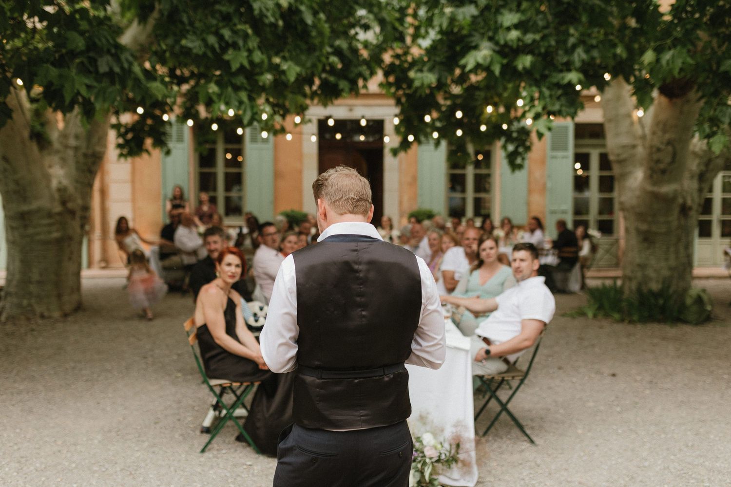 Wedding reception setup in a charming courtyard with string lights and green foliage.
