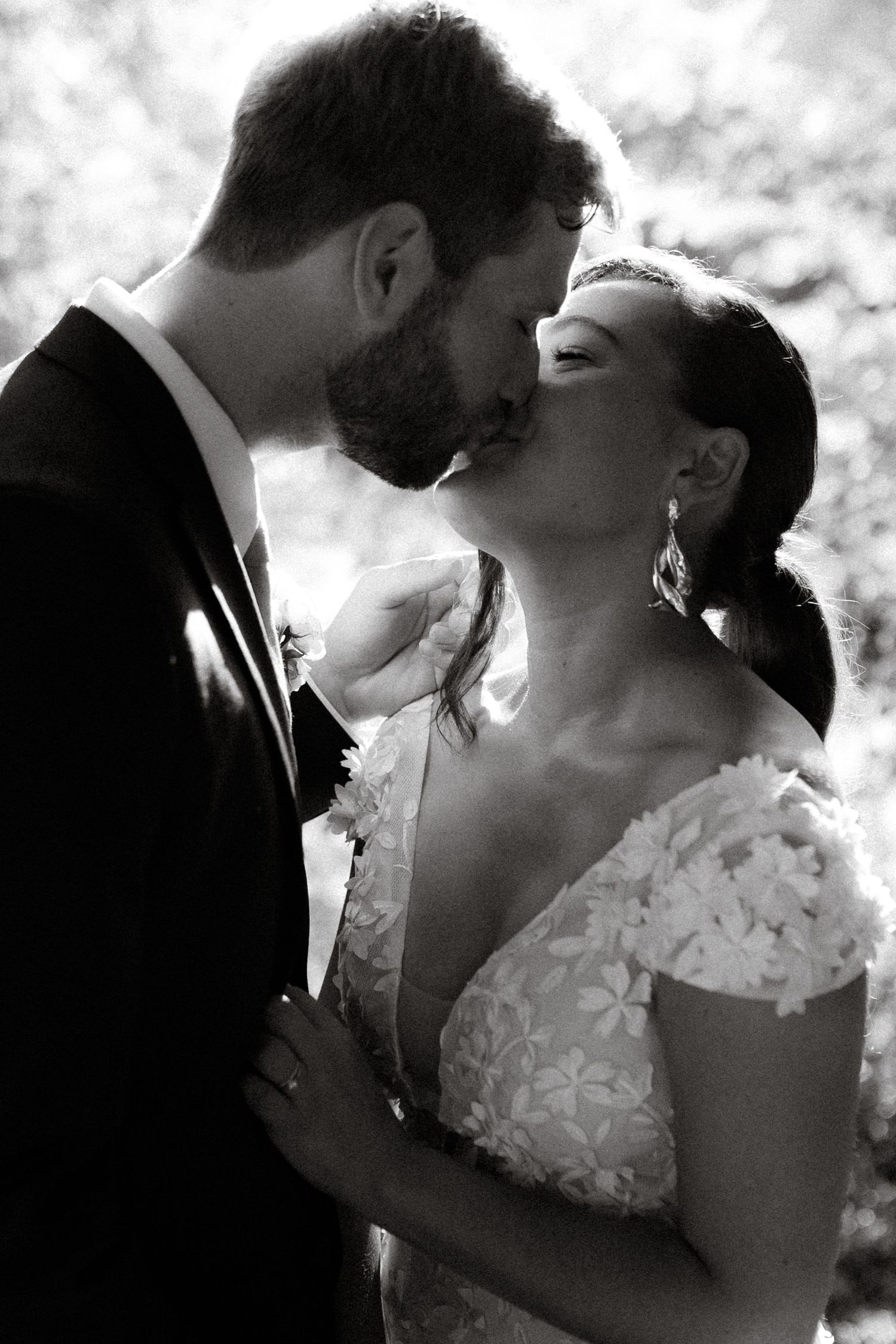 A romantic black and white wedding portrait shows a couple sharing an intimate moment in dramatic lighting.
