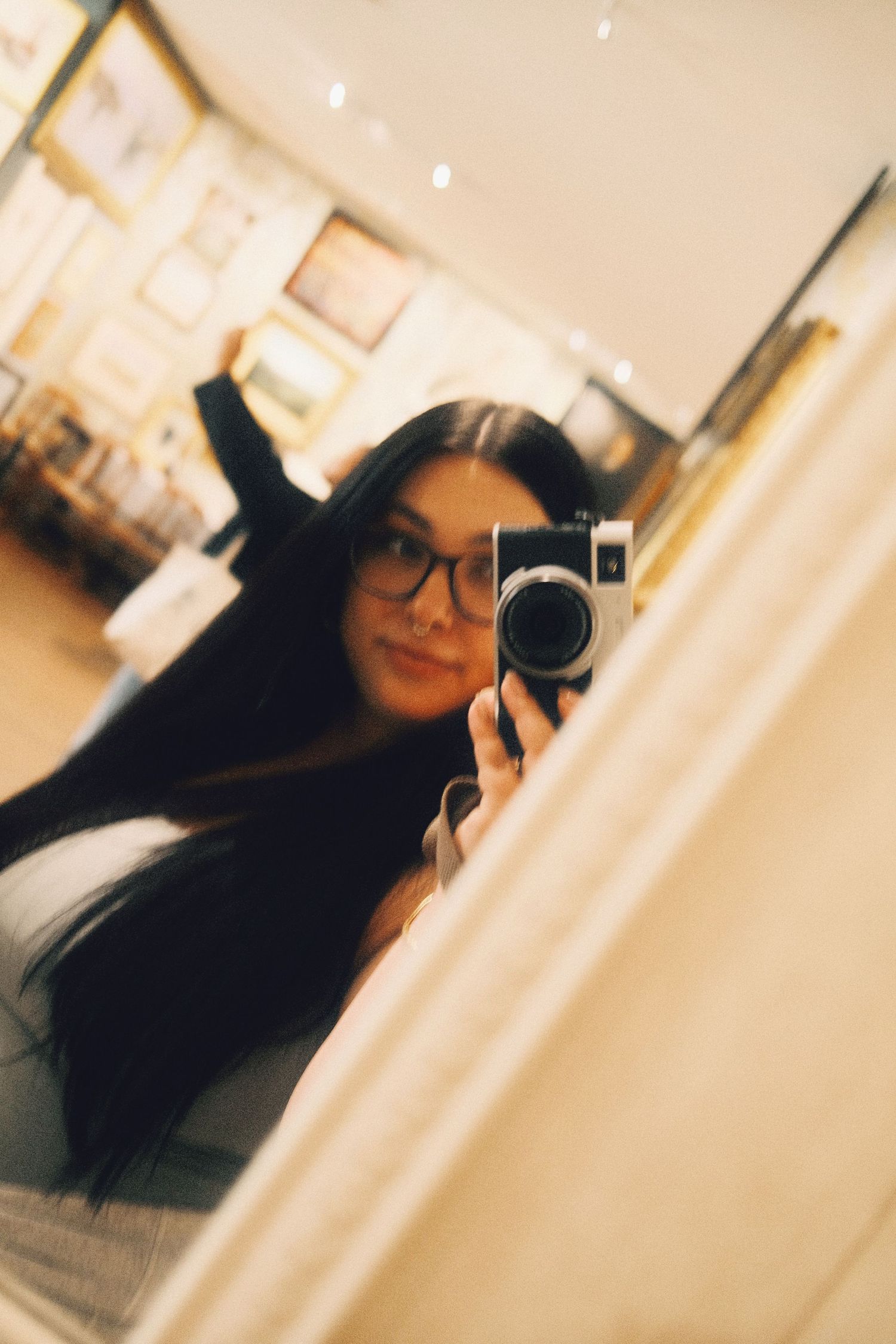 Mirror selfie showing a camera reflection in warm lighting.