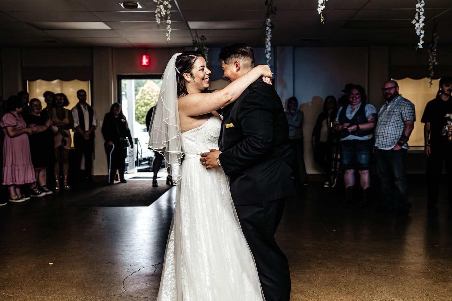 A bride and groom share their first dance together at their wedding reception in a dimly lit venue.
