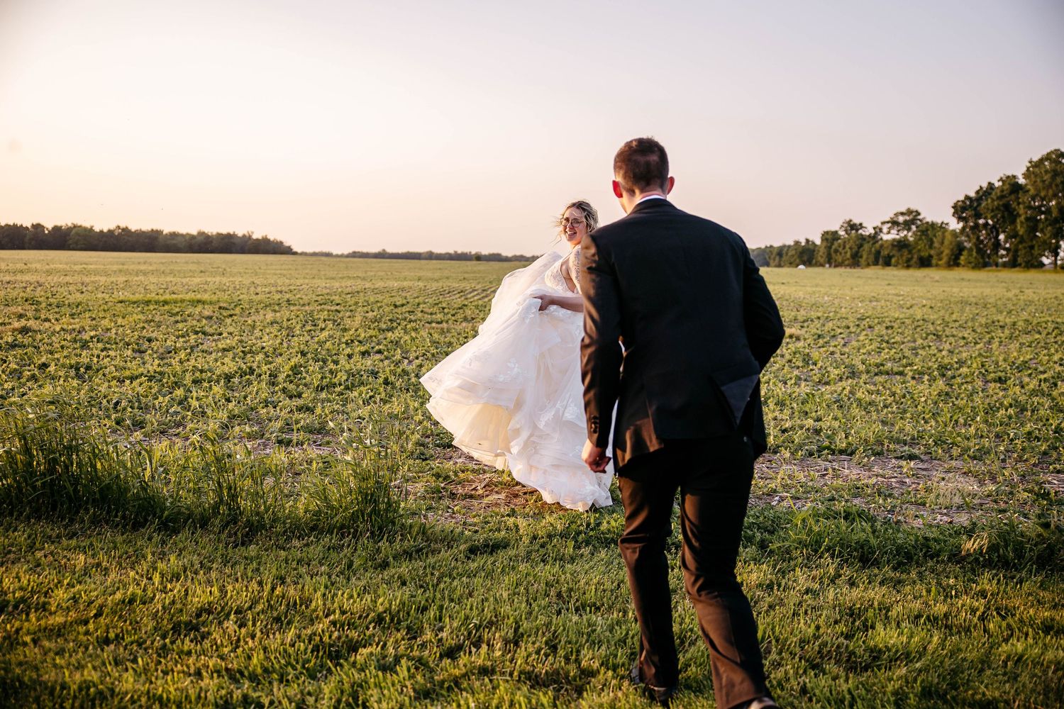 A couple embraces in a golden field at sunset creating a romantic silhouette against the horizon.