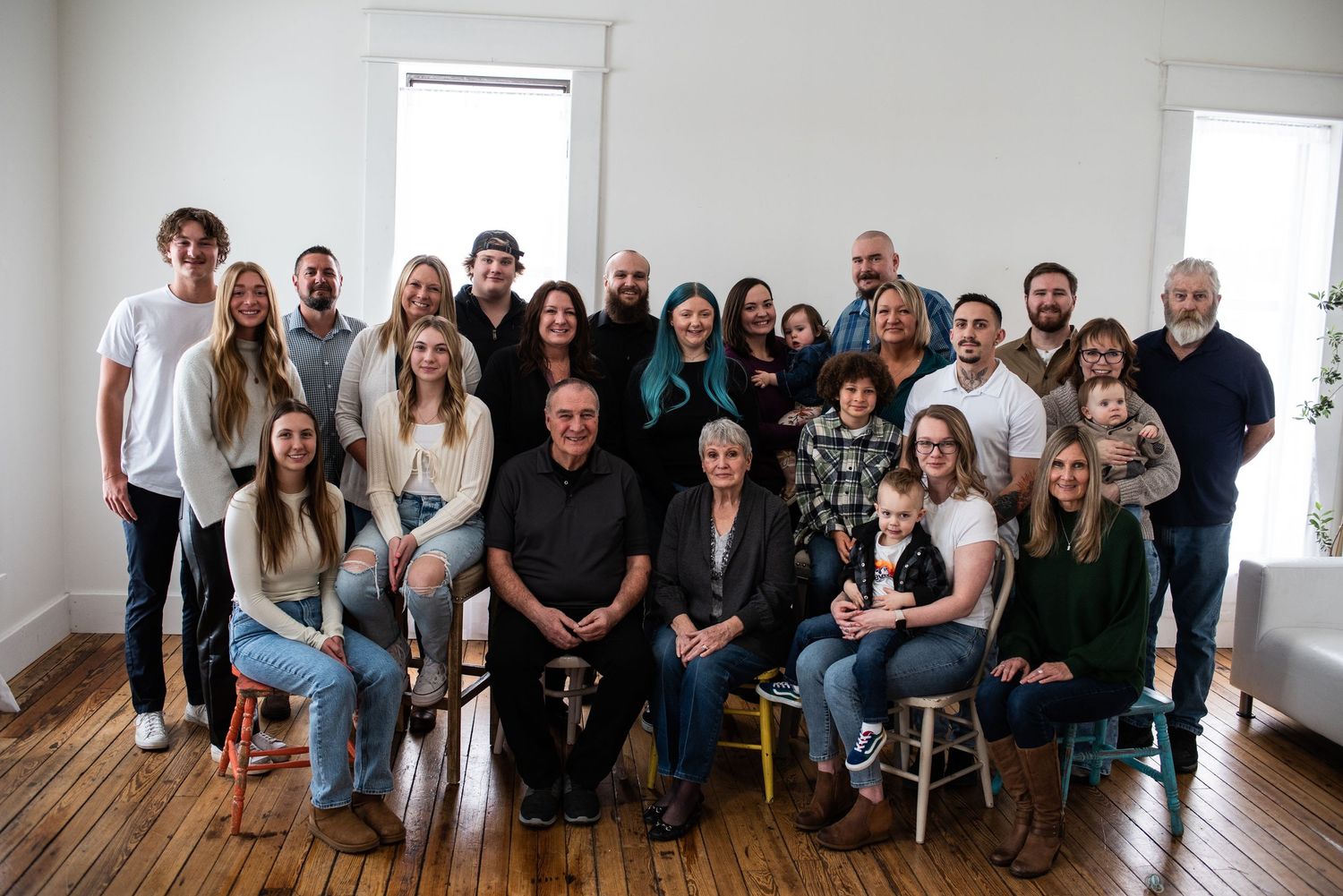 Large group photo of family and friends gathered in bright white studio space.