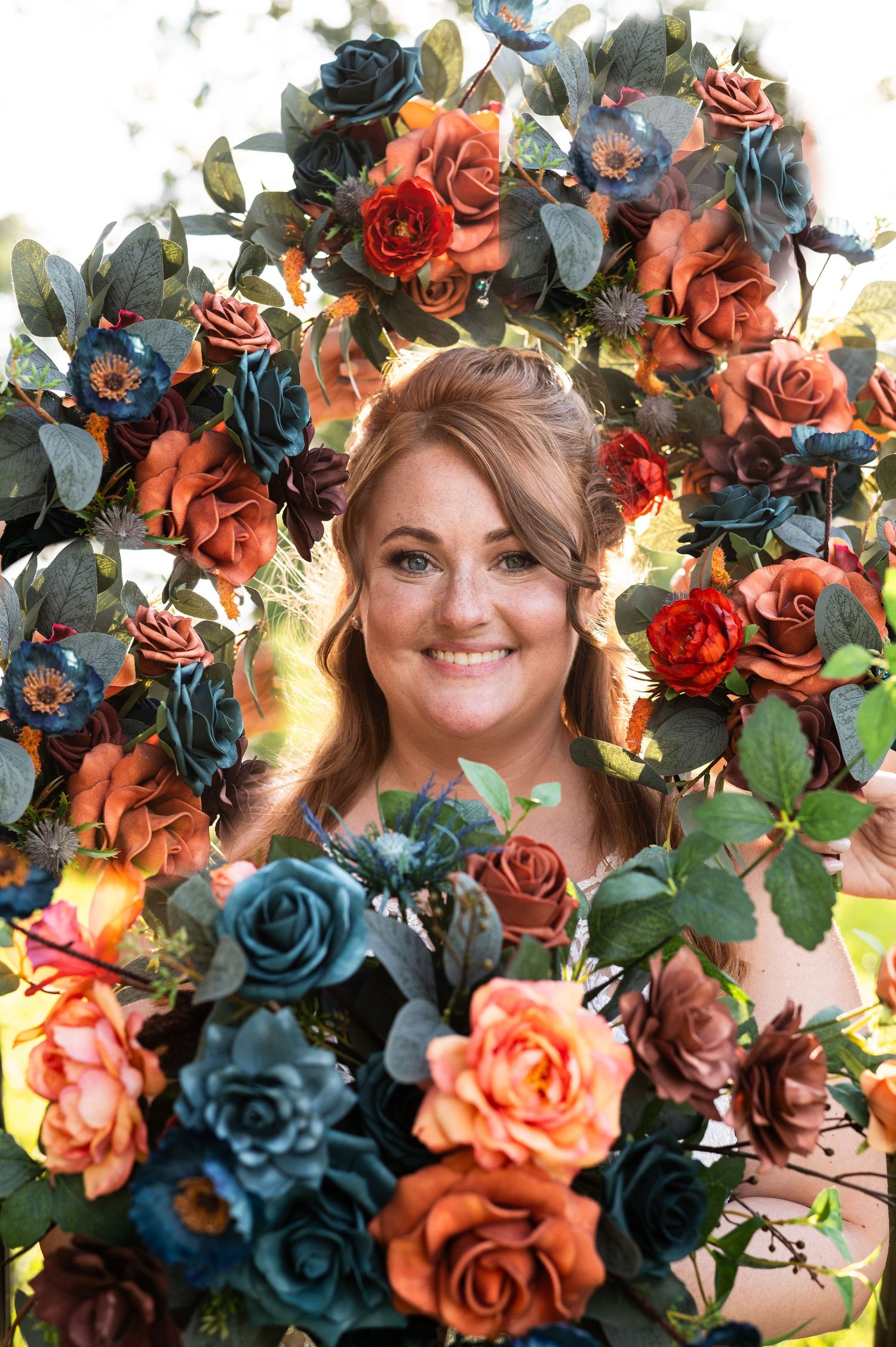 Artistic portrait surrounded by vibrant blue and coral roses with dramatic lighting.