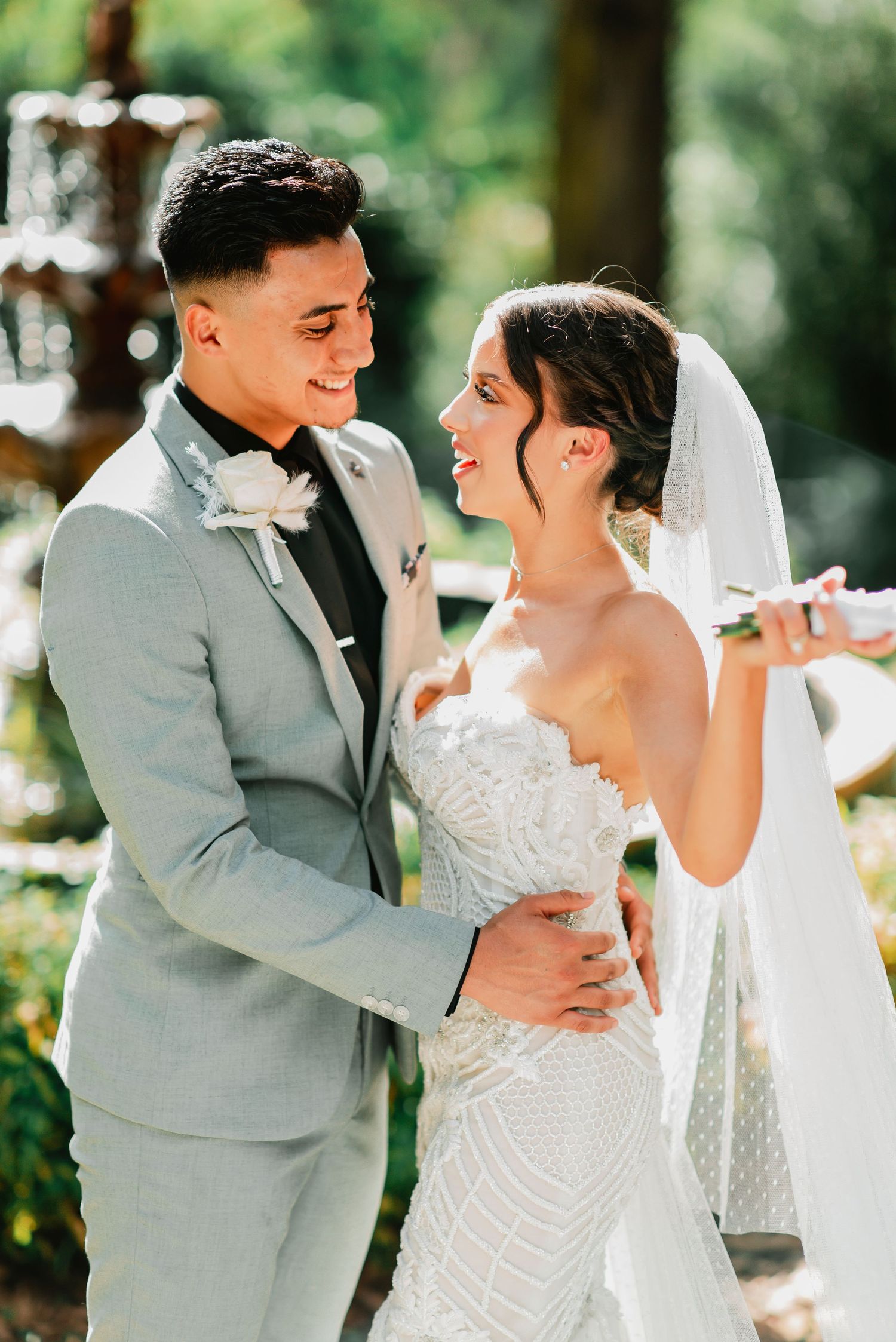 A joyful couple shares a romantic moment during their outdoor wedding ceremony, the bride in white and groom in grey.