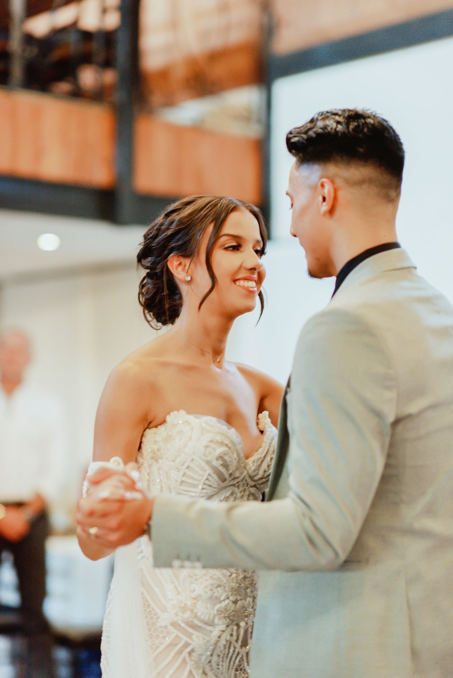 A romantic couple dancing together at their wedding reception, with the bride in a detailed white gown.