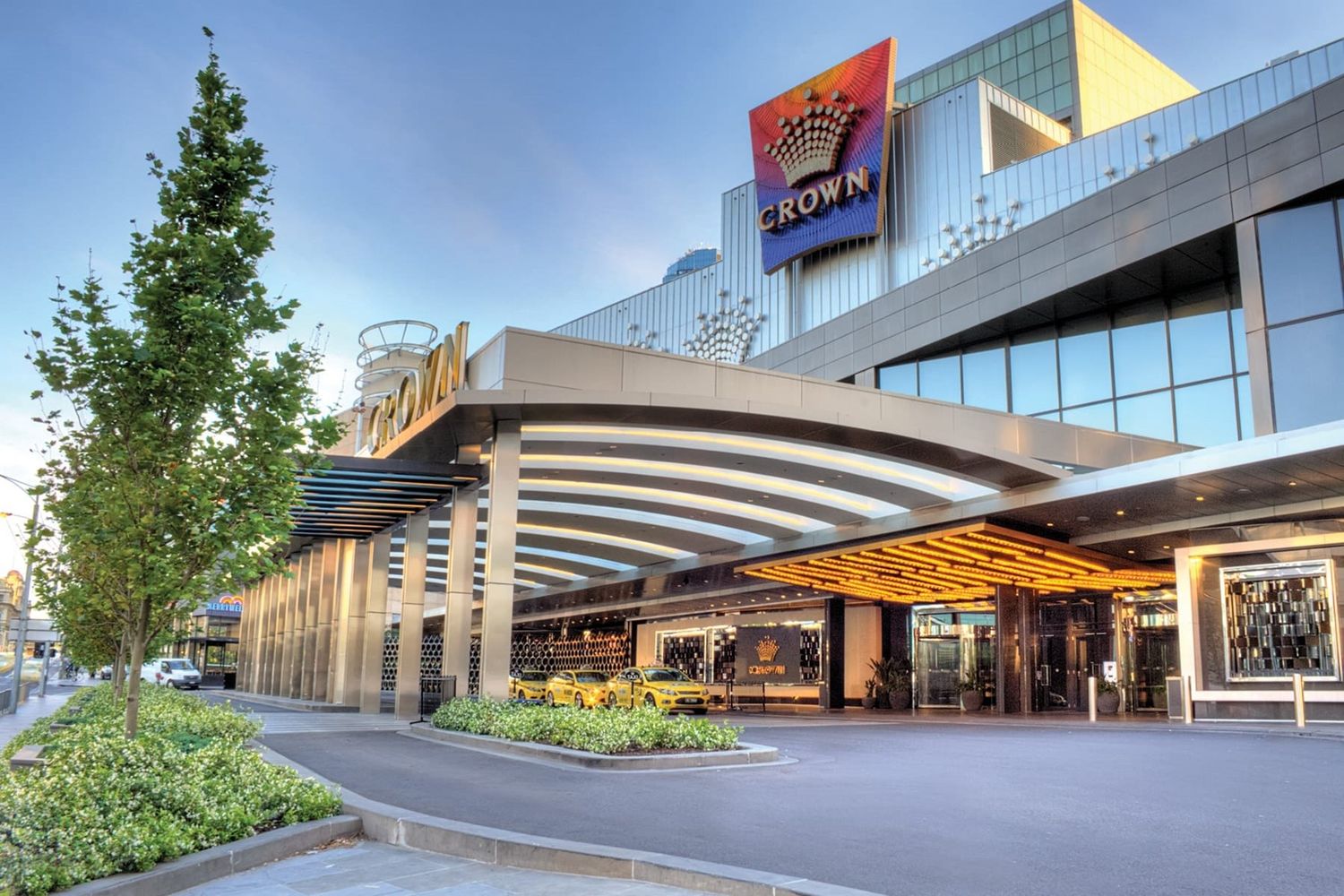 Modern entrance to Crown Casino featuring curved architecture and illuminated signage at dusk in Melbourne, Australia.