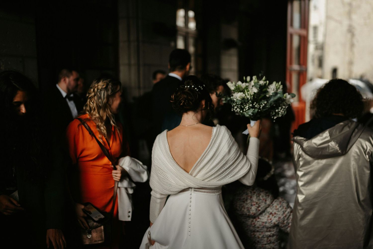 A crowd of people at a dimly lit wedding reception venue with decorative lighting creating an ambient atmosphere.