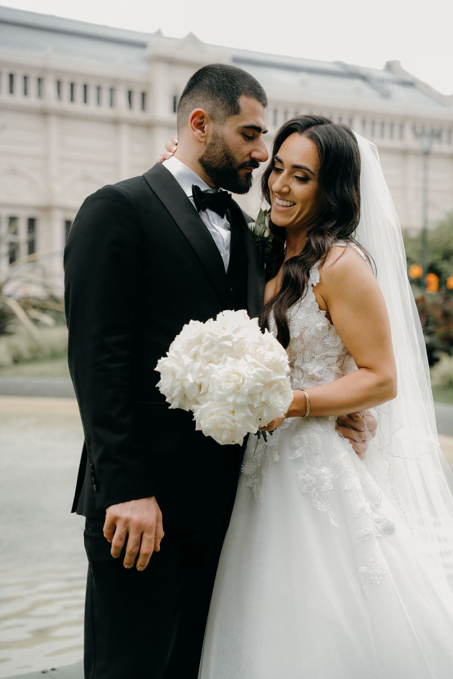 A joyful wedding celebration with a couple sharing an intimate moment as the bride holds a white hydrangea bouquet.