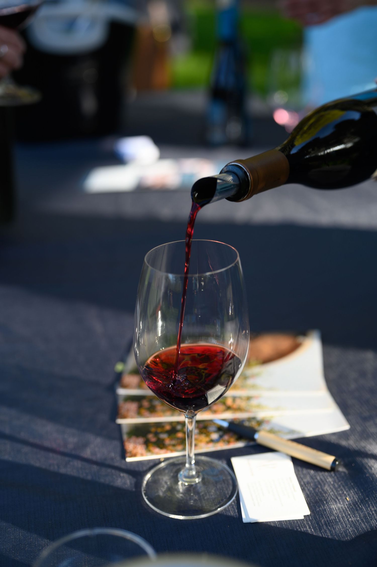Red wine being poured into an elegant wine glass on a dark table with soft background blur.