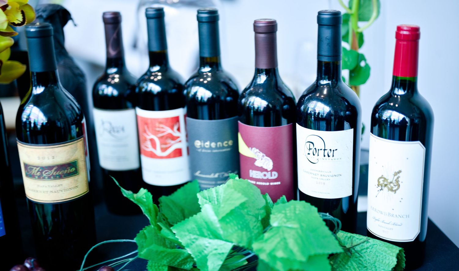 Collection of wine bottles arranged in rows on display showing various red and white wine varieties.