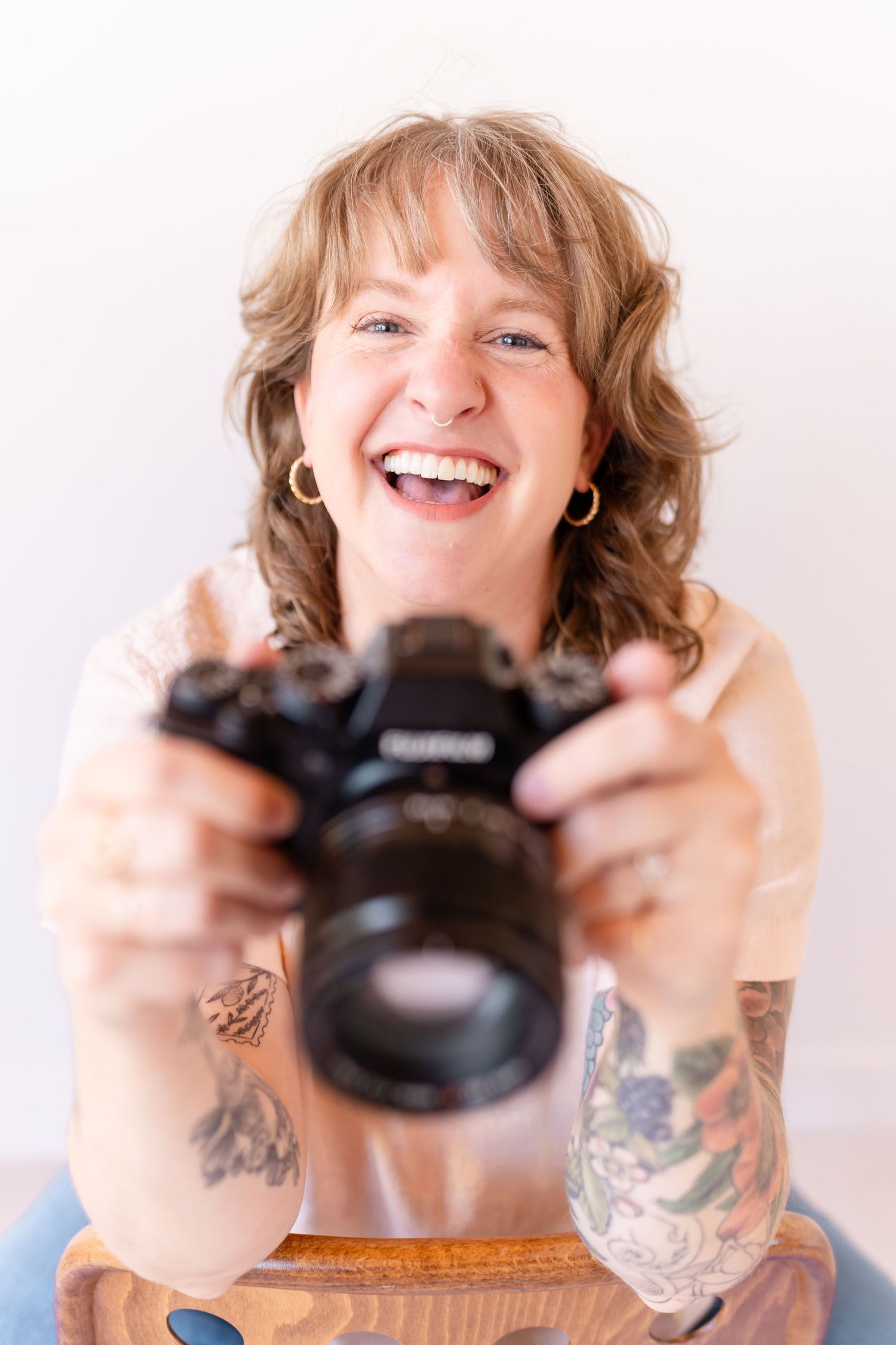 Person with tattoos holding and kissing small black cat while smiling in sequence of bright white photos.