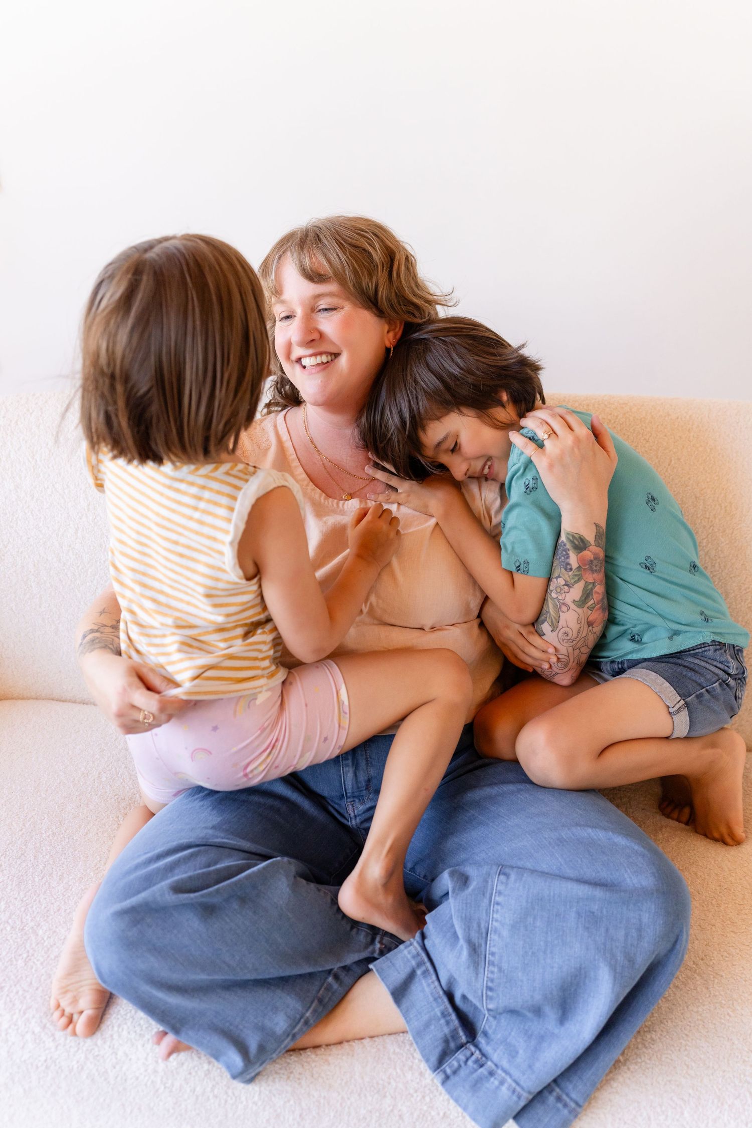 A joyful moment of affectionate play and laughter on a light-colored sofa.