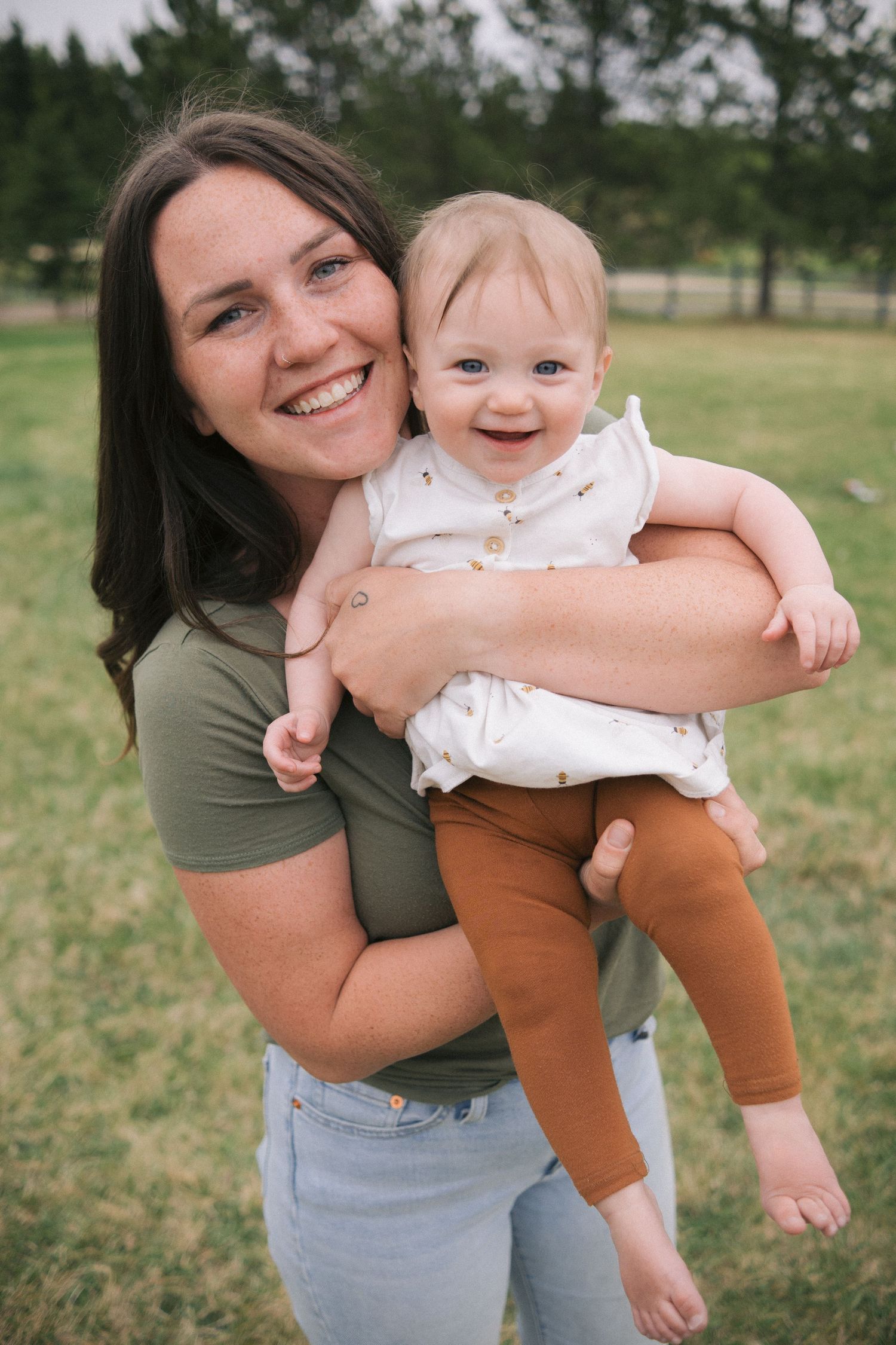 Parent and baby sharing sweet moments together in a green outdoor setting.