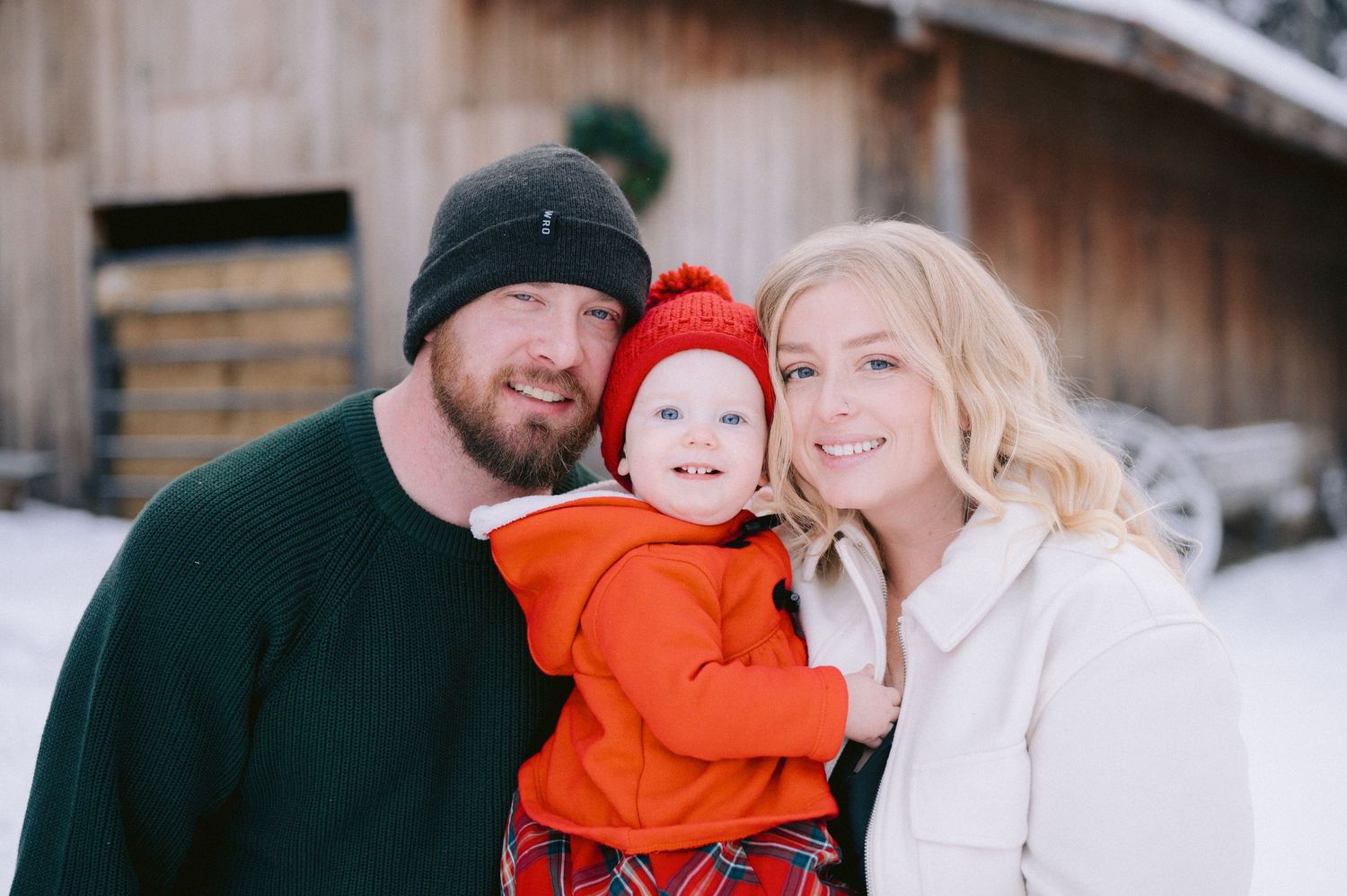 Family portrait in winter with small child wearing bright orange coat.