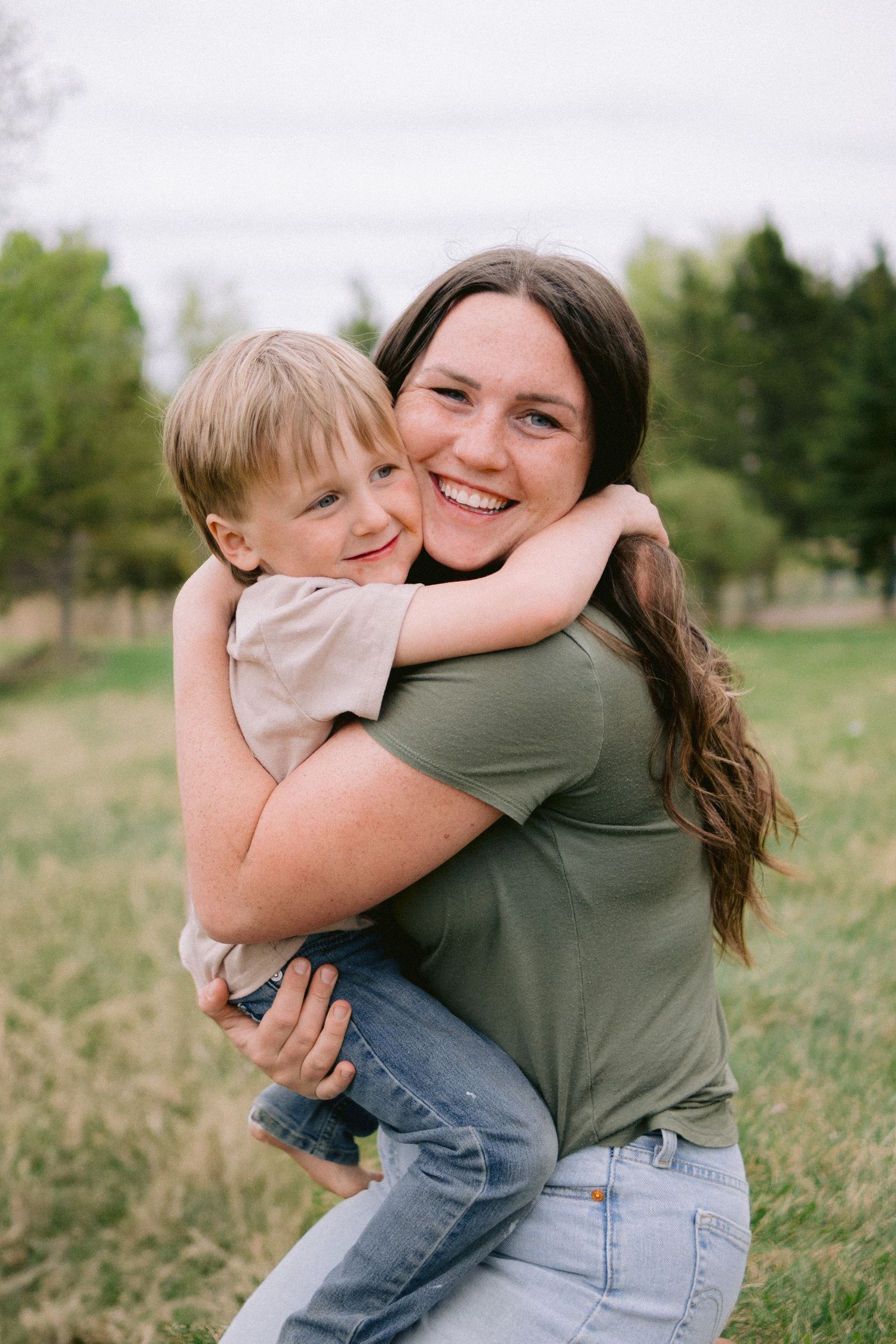 Joyful embraces between parent and child in a sunny outdoor field.