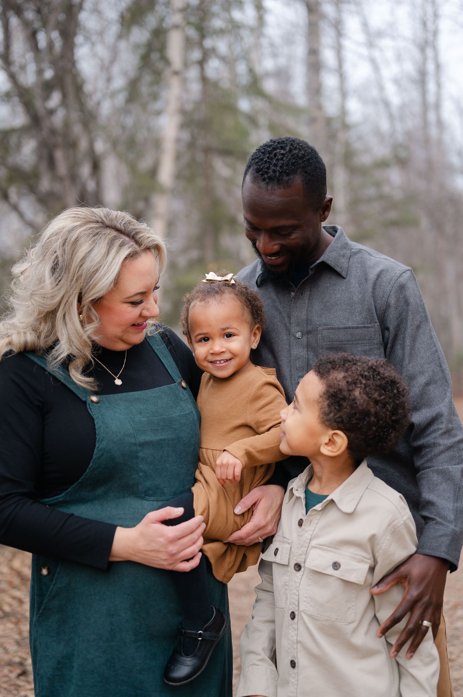 Family portrait session showing parents sharing loving moments with their children outdoors.