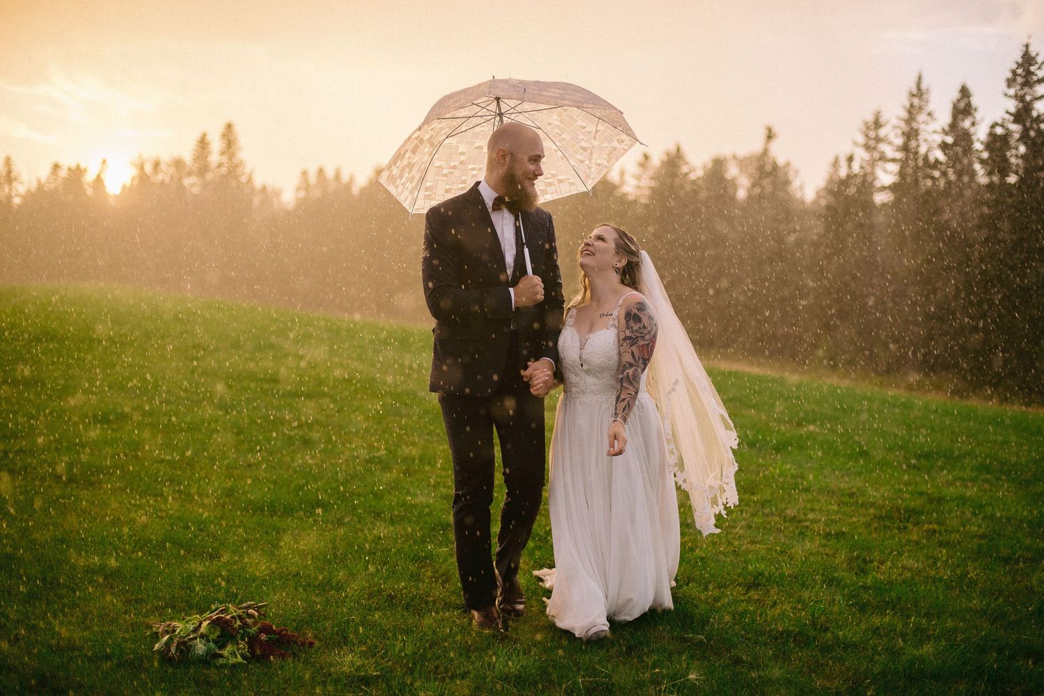 Couple shares a tender moment at sunset in a golden-lit field during their wedding.