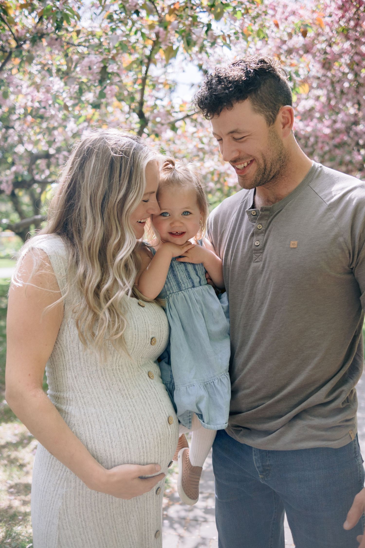 Happy family sharing joyful moments together under pink cherry blossoms.