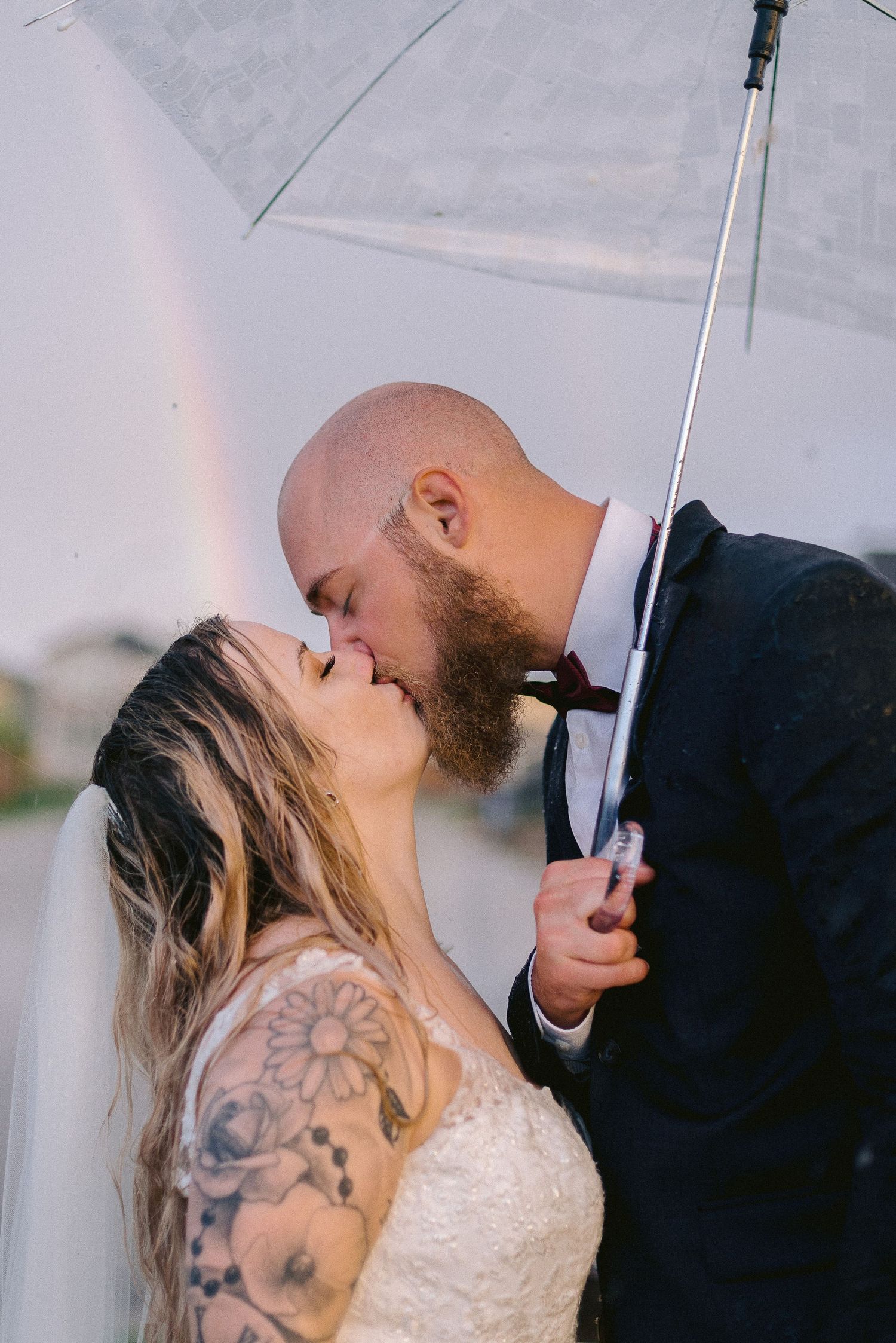 A romantic couple shares a kiss under a white umbrella in a series of intimate wedding photos.