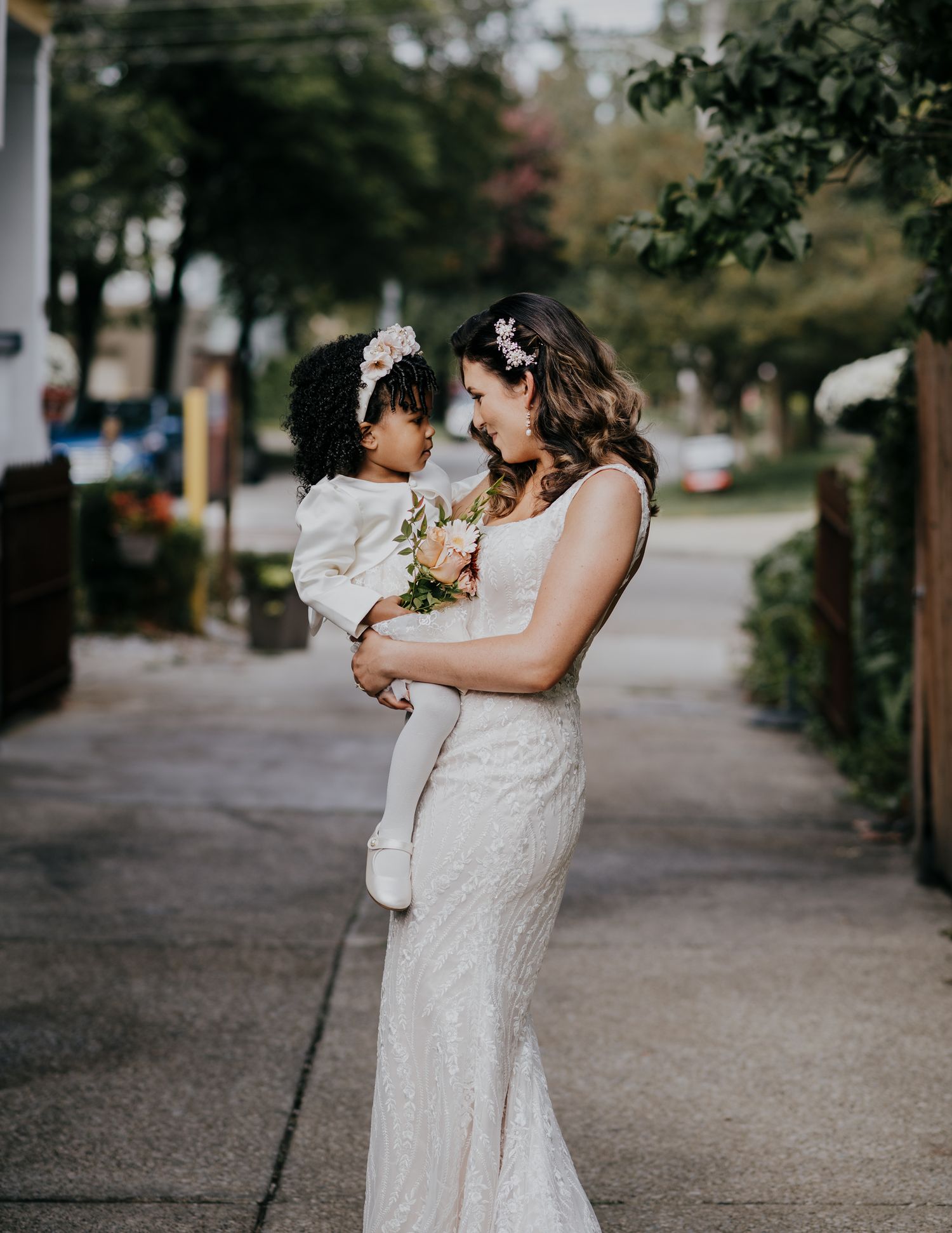 A series of tender moments captured at a wedding featuring two people embracing in white lace dresses on a walkway.