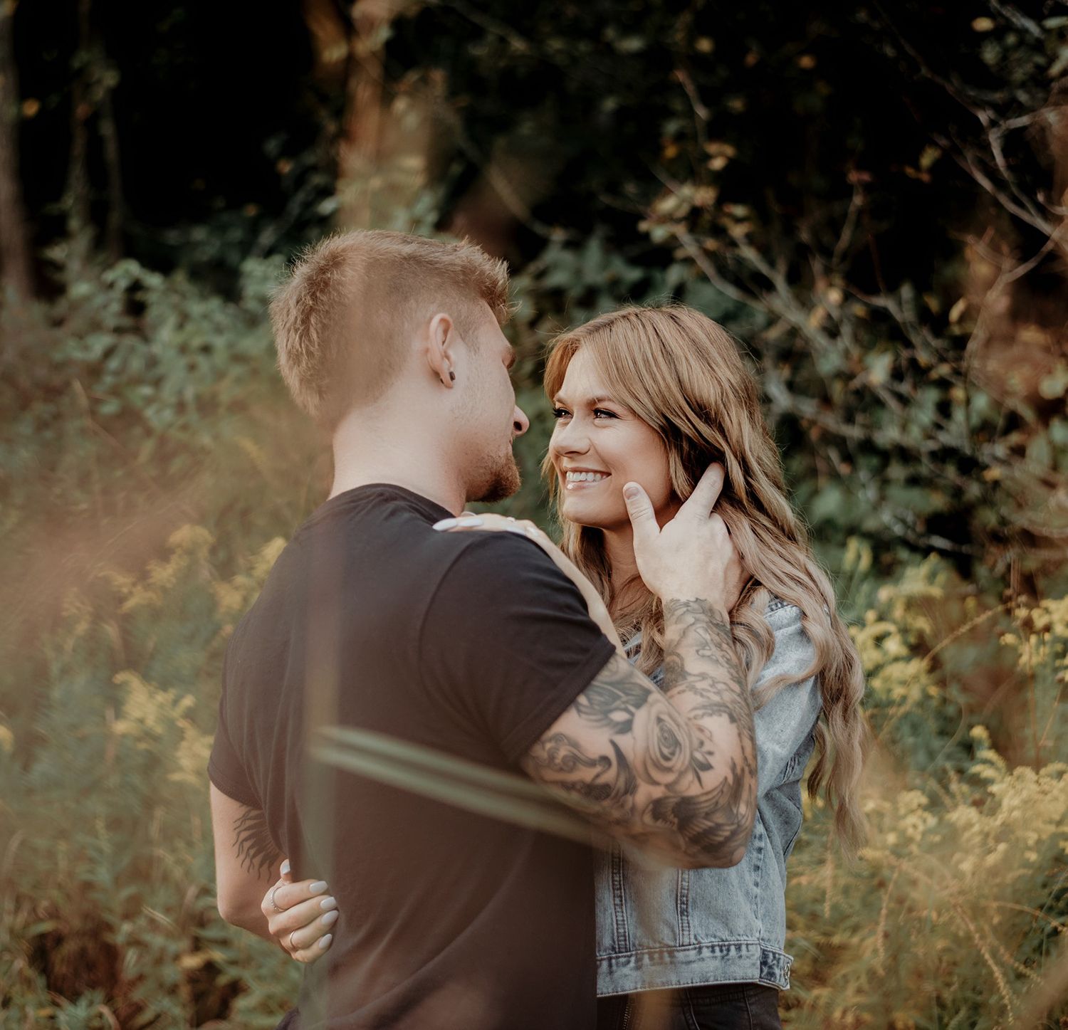 A romantic couple sharing an intimate moment in a dreamy forest setting during golden hour.