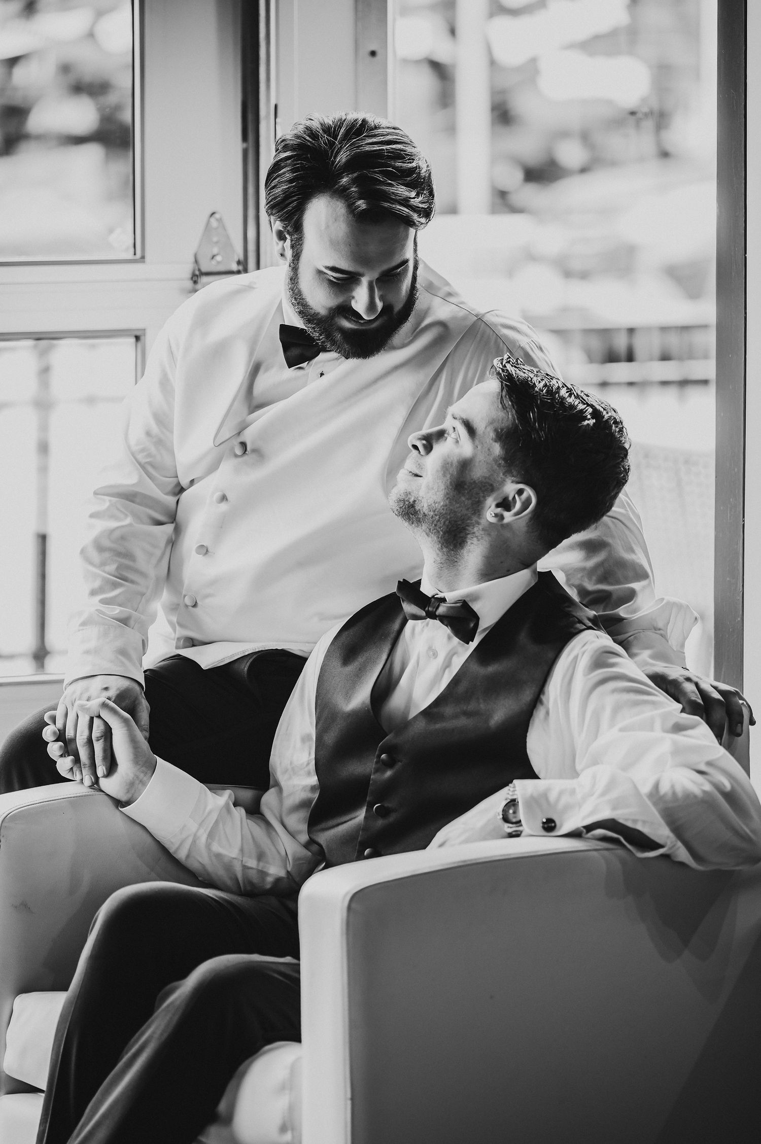 Black and white photograph of two men in formal attire with bow ties sitting in an elegant room.