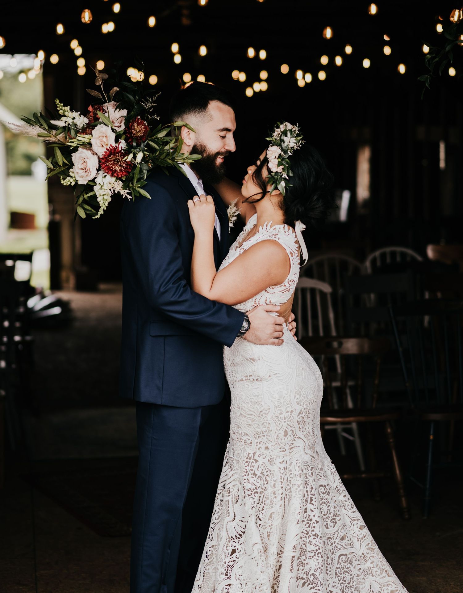 A couple dances intimately under glowing string lights at an evening wedding reception.