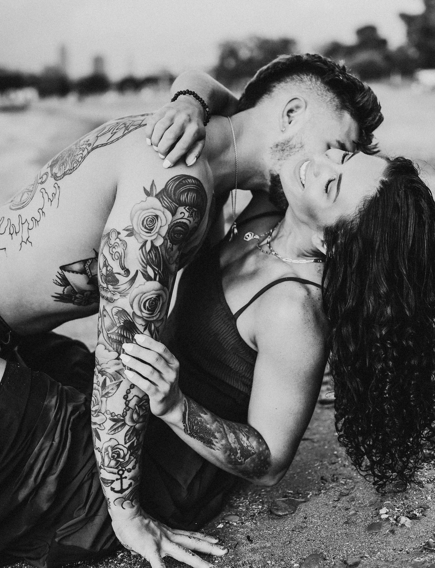 A black and white artistic series featuring several close-up shots of a person with tattoos lying on the ground.