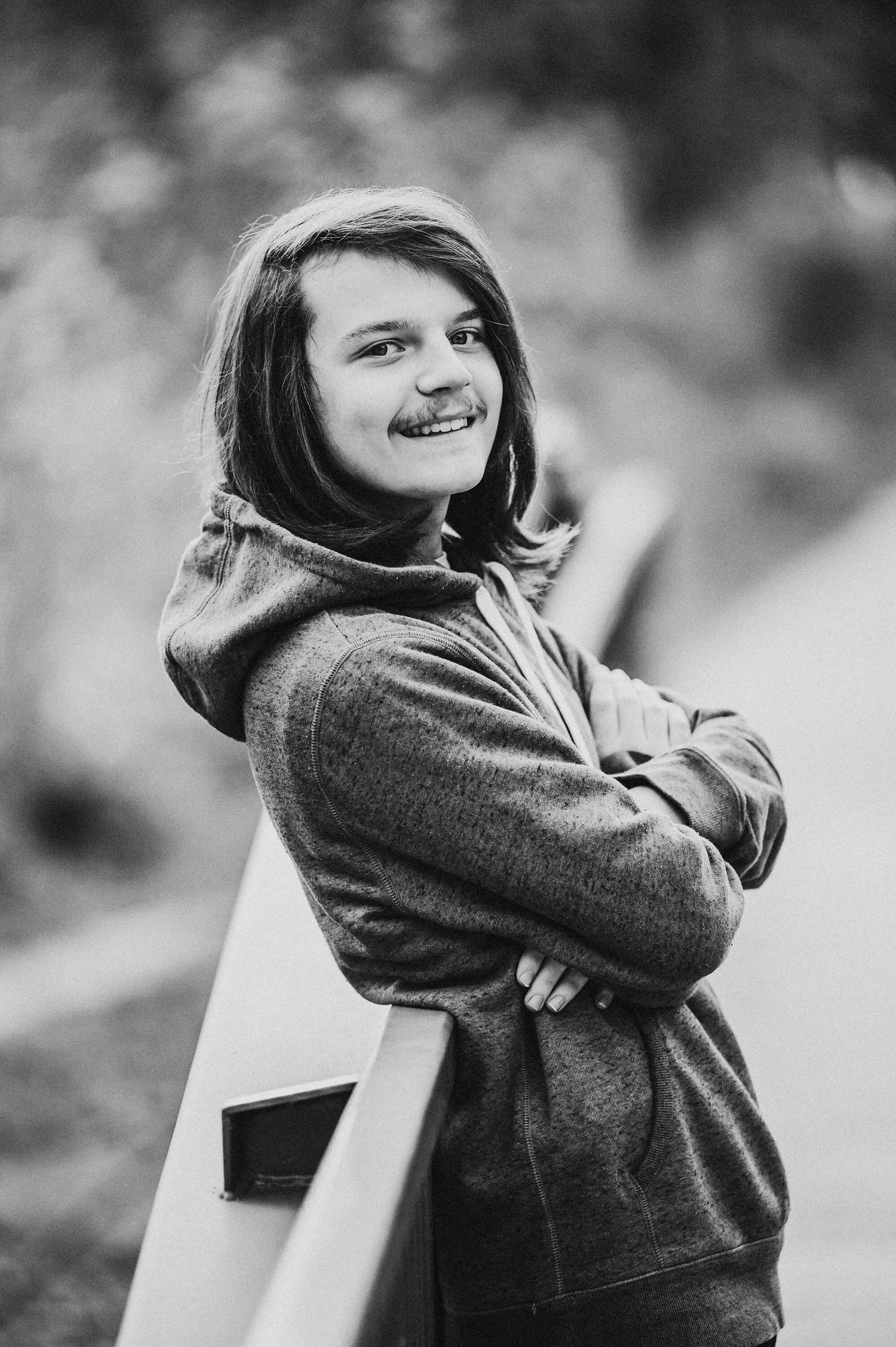 A person in a gray sweater sits on a white bench and looks back over their shoulder in a black and white photograph.
