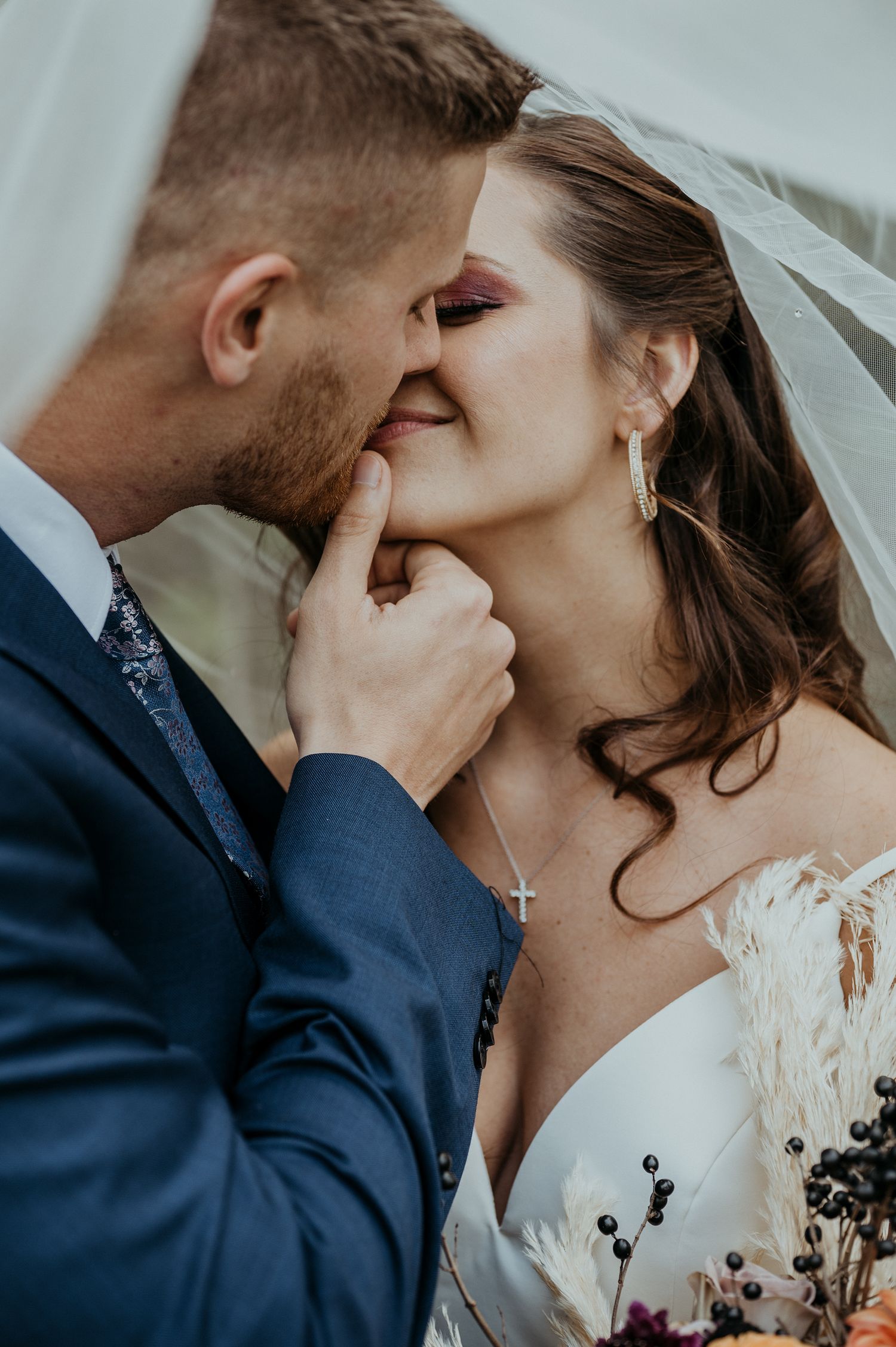 Close up sequence of a tender kiss between newlyweds, with the bride in lace and groom in navy suit.