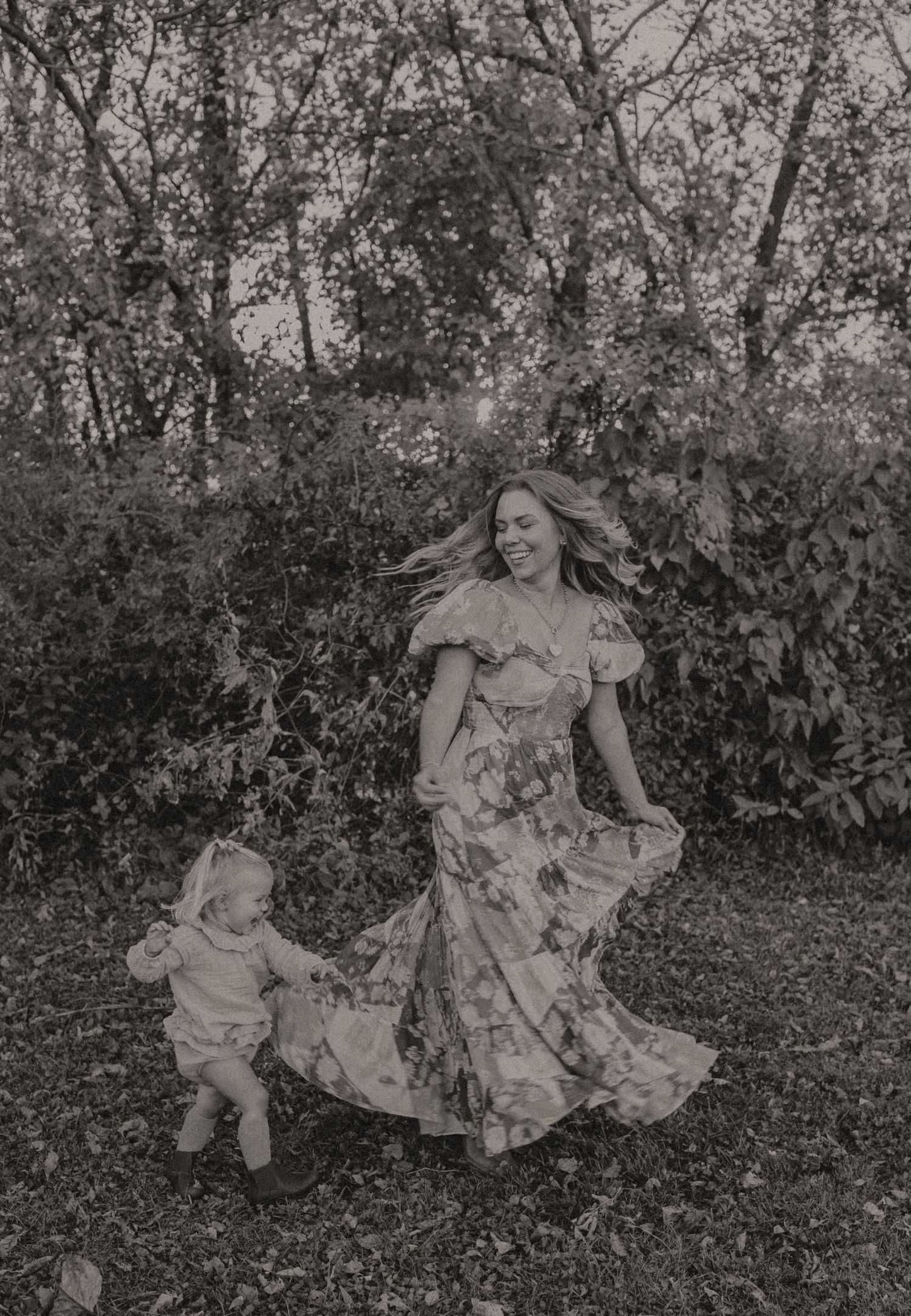 Black and white photo of dancing in flowing dress through garden.