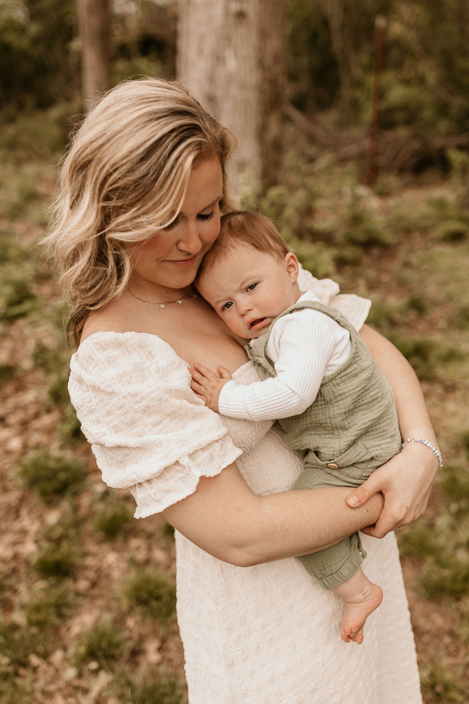 An intimate portrait of maternal love as a woman in white holds her baby close in nature.