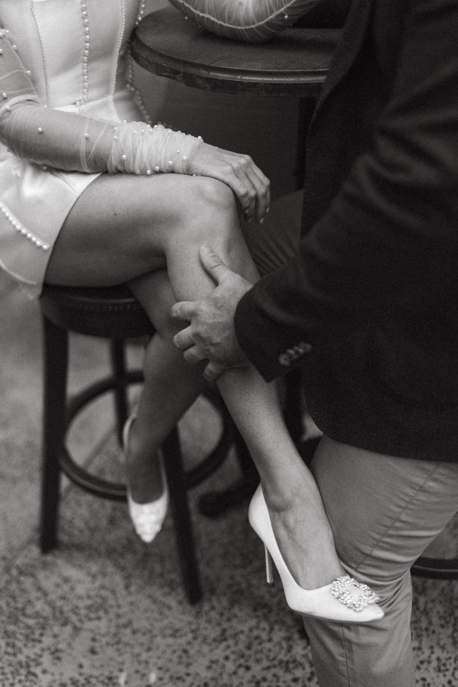 Black and white series of three photos showing feet being crossed while sitting, capturing a casual intimate moment.